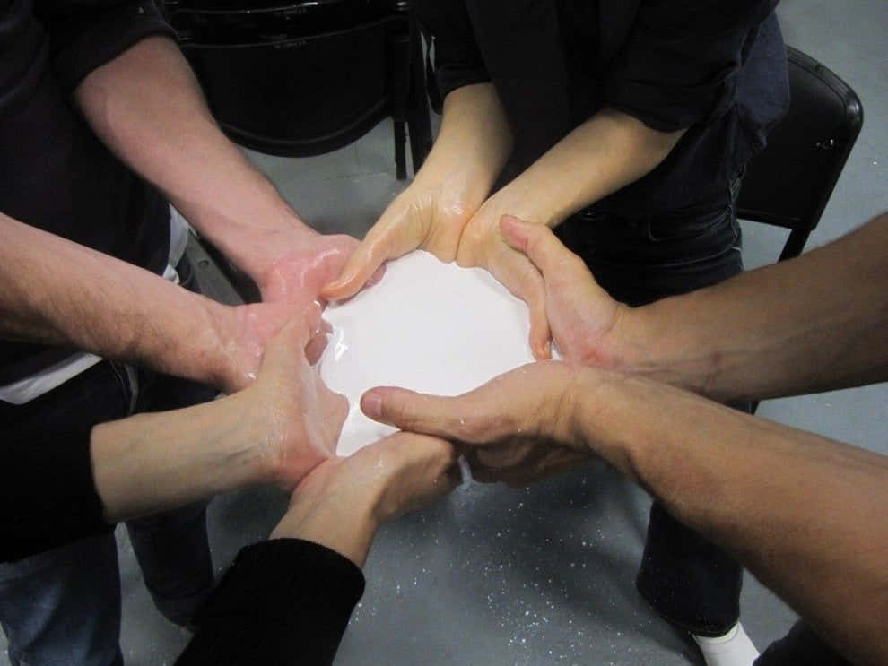 Teamwork Memes 桌布 壁紙 — 多隻手圍繞著一種白色黏稠物質形成一個圓圈，暗示團隊合作或儀式。