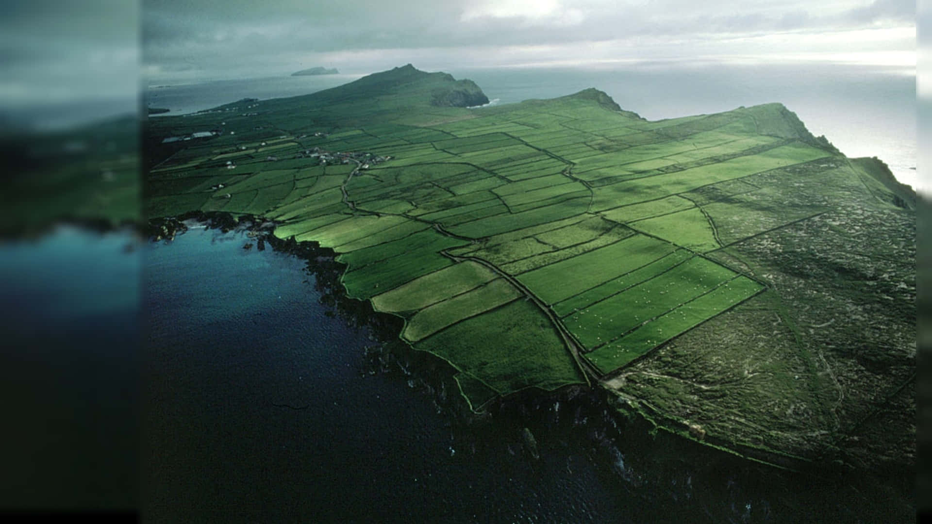 海岸島嶼上綠色農田的鳥瞰圖，有懸崖和海洋。