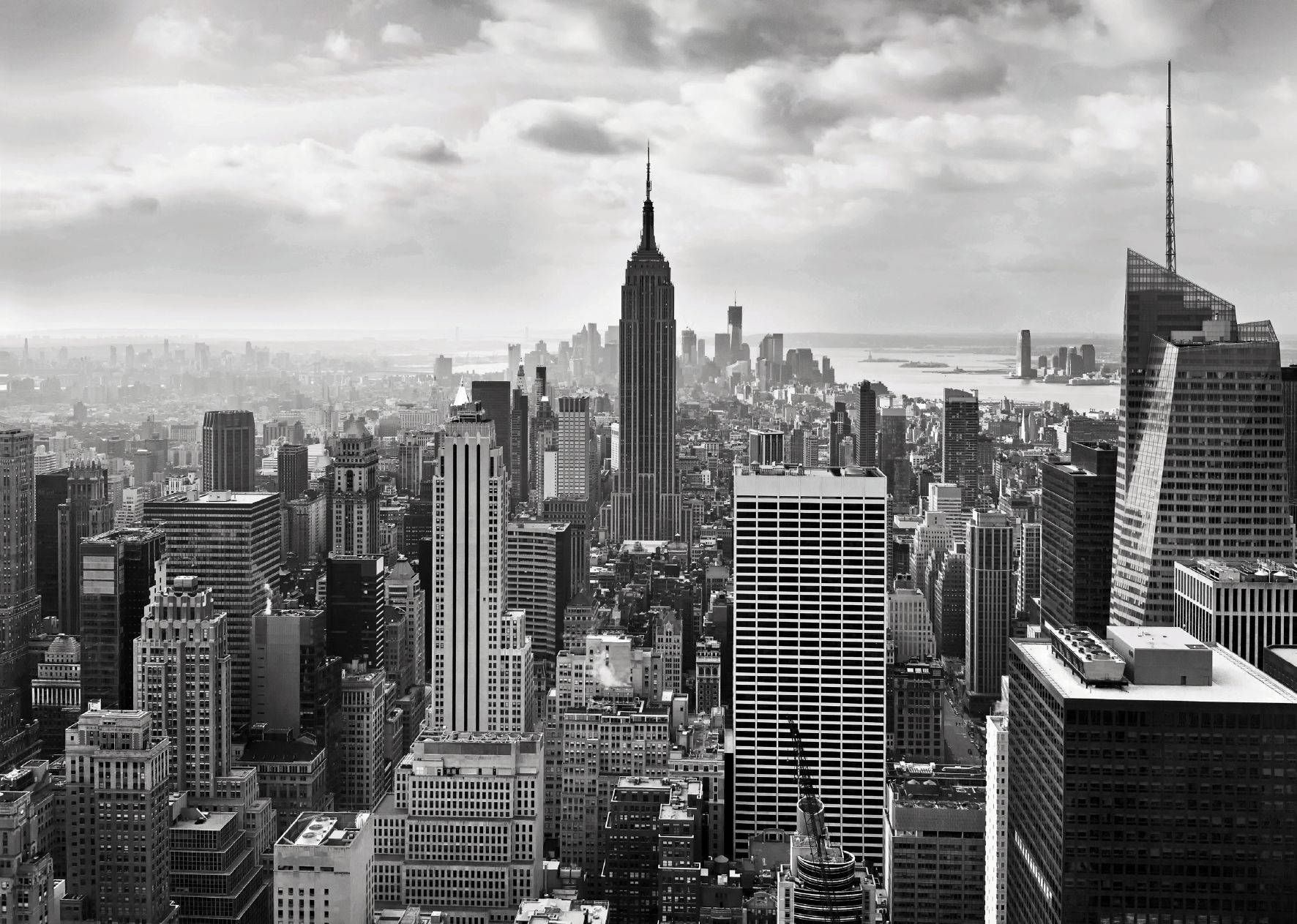 New York 桌布 壁紙 — 多雲天空下，帝國大廈主導的紐約市天際線黑白航拍視圖。