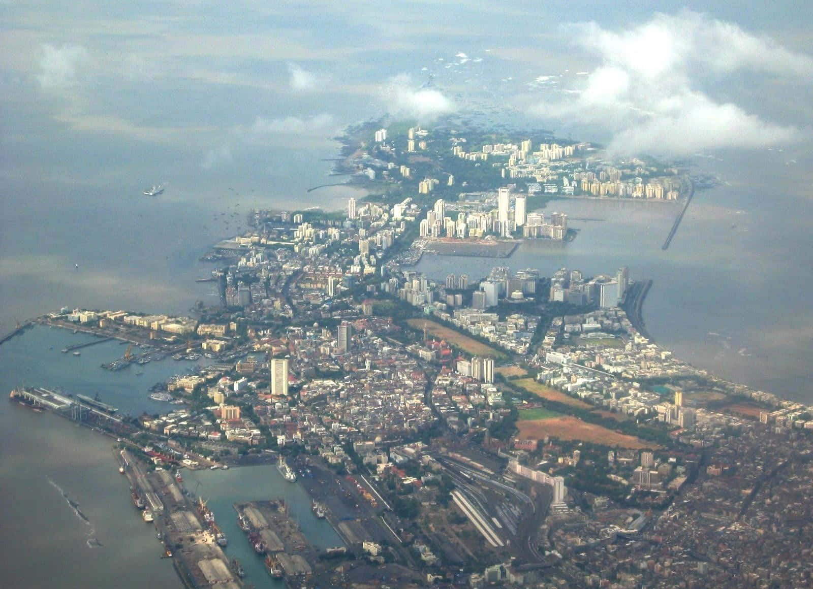 孟買 桌布 壁紙 — 多雲天空下，沿海城市密集的城市擴張、港口和水道的鳥瞰圖。