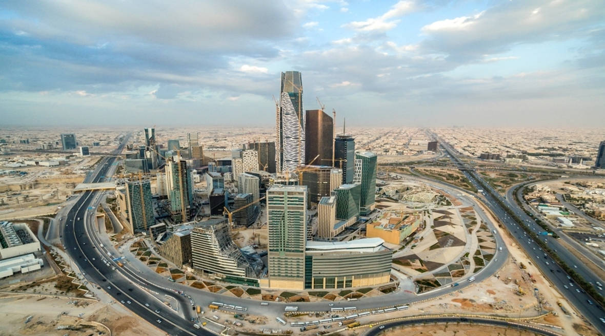 Riyadh 桌布 壁紙 — 多雲天空下，現代城市景觀的鳥瞰圖，高聳的摩天大樓和彎曲的高速公路。