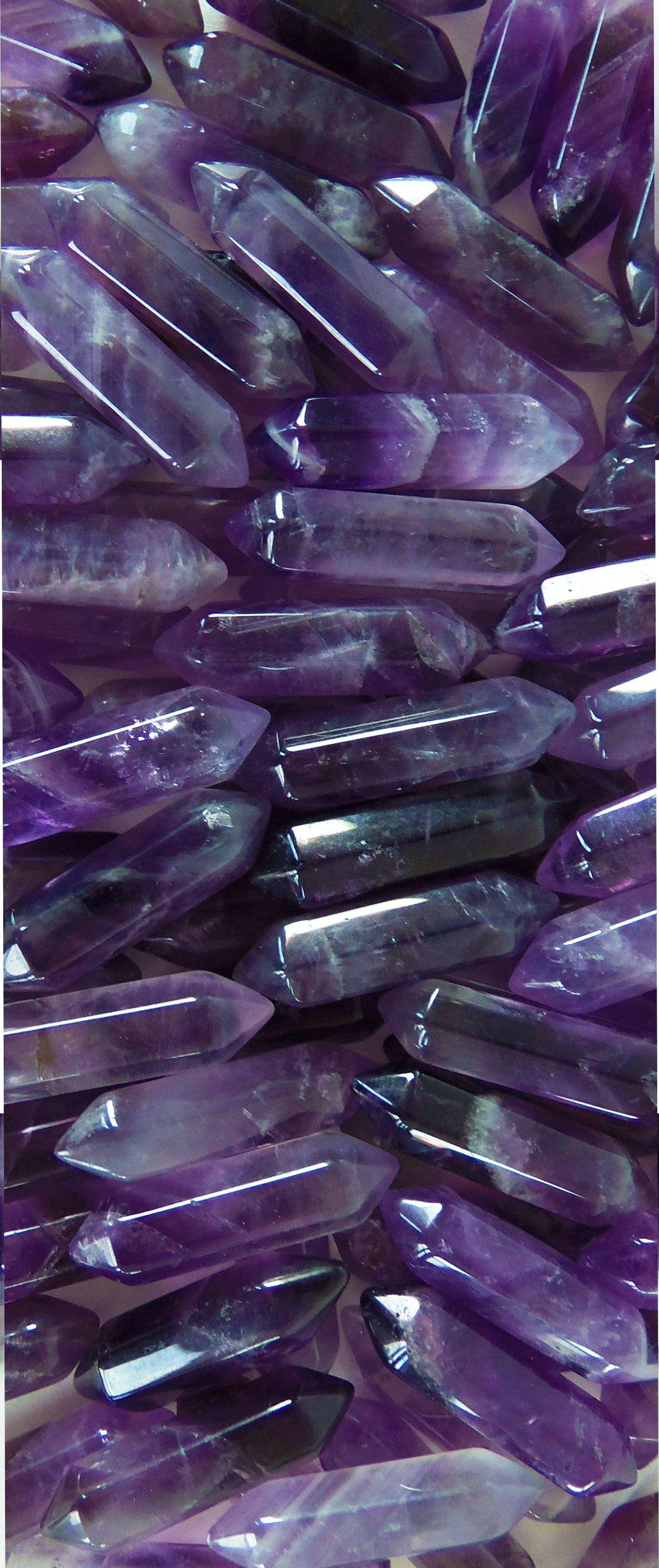 紫水晶 桌布 壁紙 — 多顆拋光紫色紫水晶晶體的近距離特寫，具有尖銳的尖端和半透明的刻面，捕捉光線。