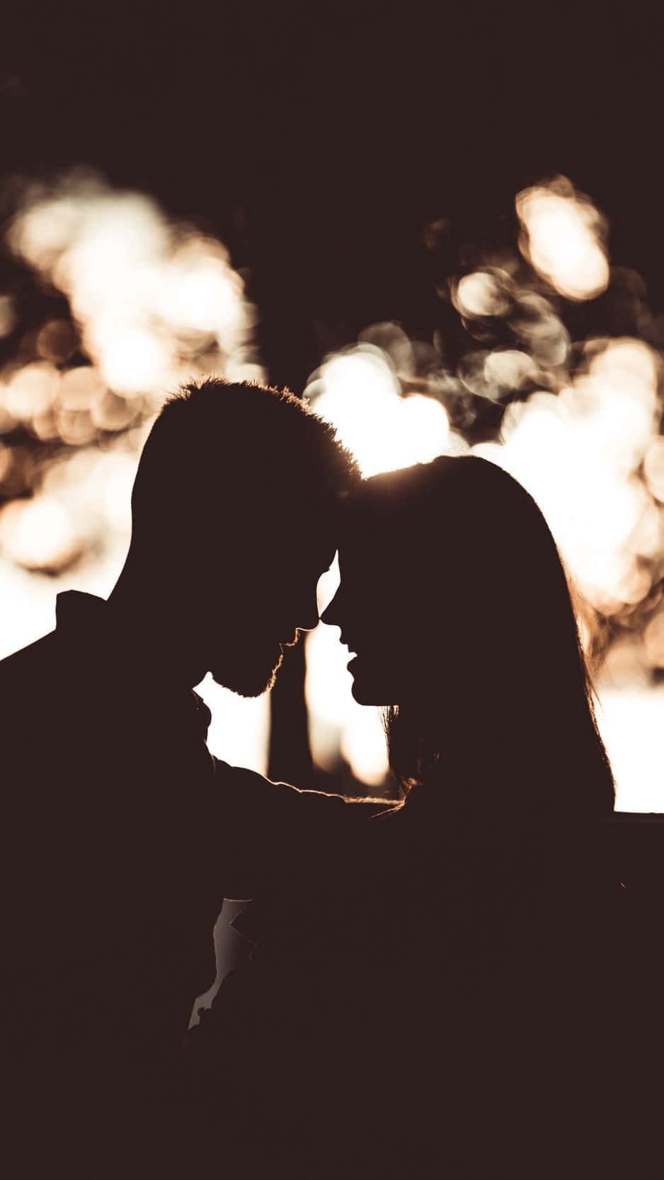 Black Couple 桌布 壁紙 — 夜幕下，剪影情侶在閃爍的散景燈光中溫柔相擁。