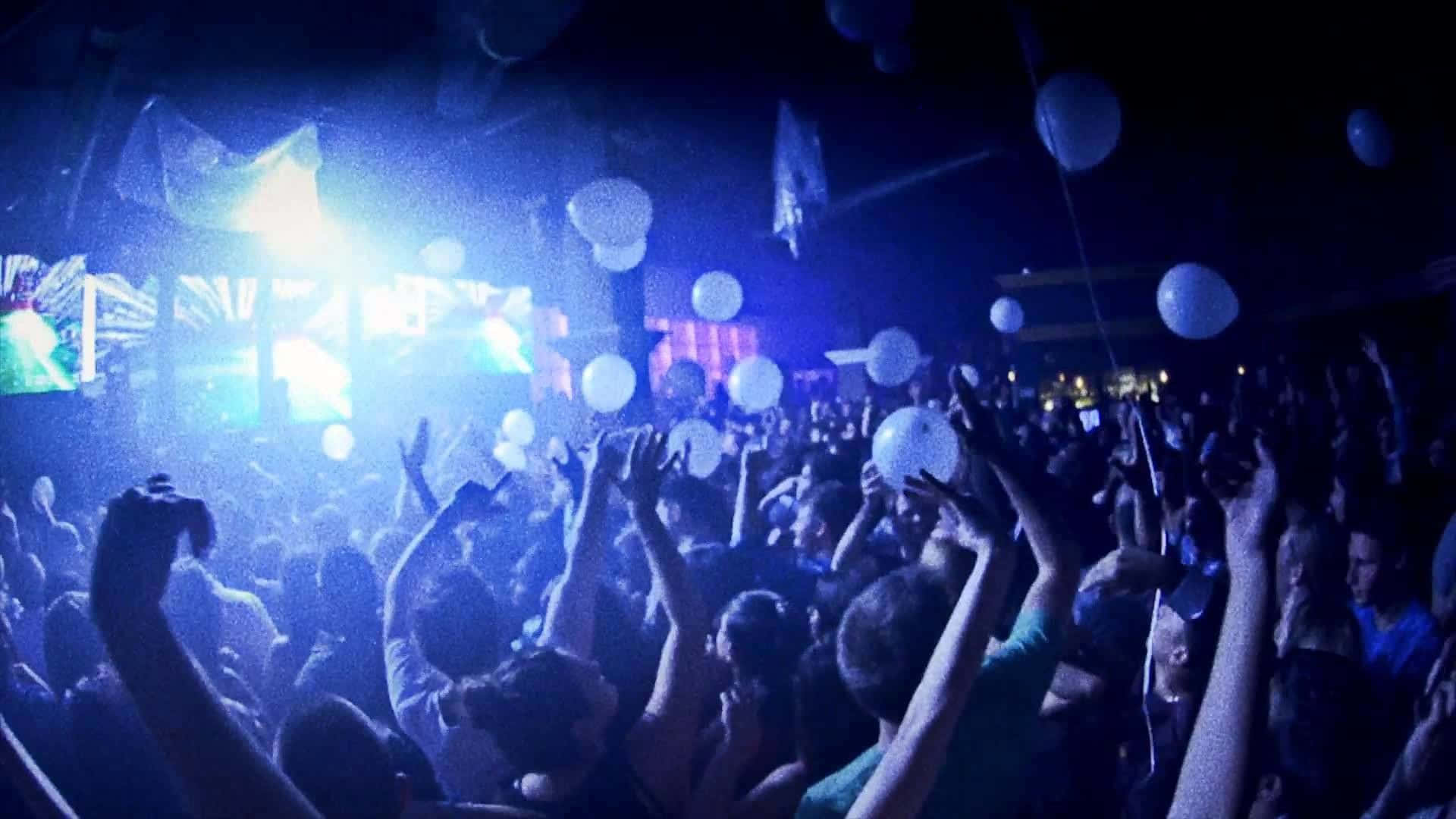 club 桌布 壁紙 — 夜店人群在閃爍藍光下跳舞，白色氣球漂浮在上方。
