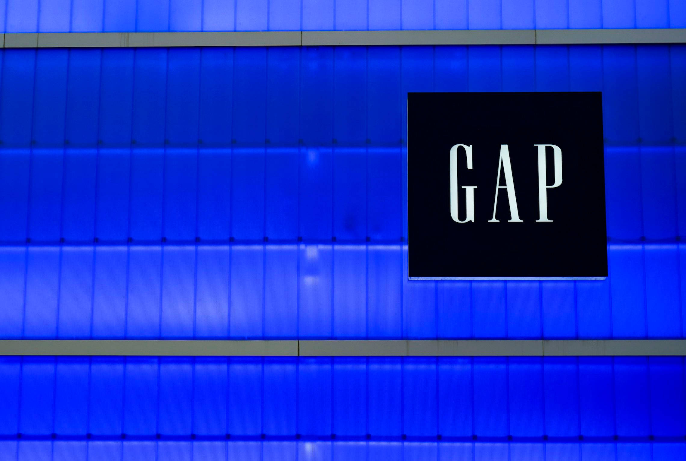 Gap 桌布 壁紙 — 夜晚，GAP 商店標誌在充滿活力的藍色鑲板建築外牆上發出白色光芒。
