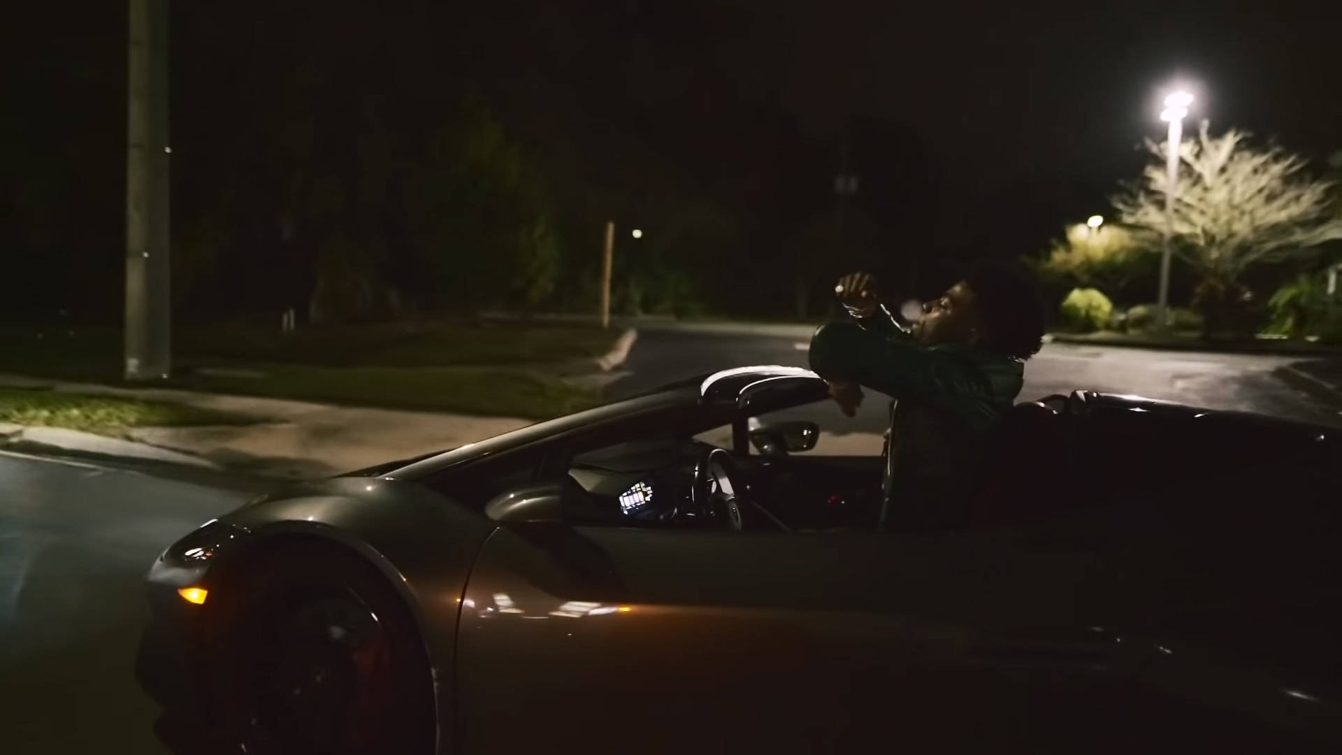 說唱歌手 桌布 壁紙 — 夜晚，一個人從時尚的黑色敞篷車探出身子，在街燈下高舉雙臂慶祝。