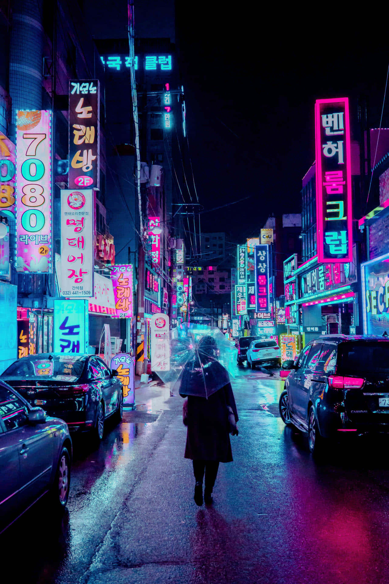 Neon Aesthetic Phone 桌布 壁紙 — 夜晚，一個孤獨的身影撐著傘走在被雨水浸濕的霓虹燈街道上，周圍是發光的韓文招牌和停泊的汽車。