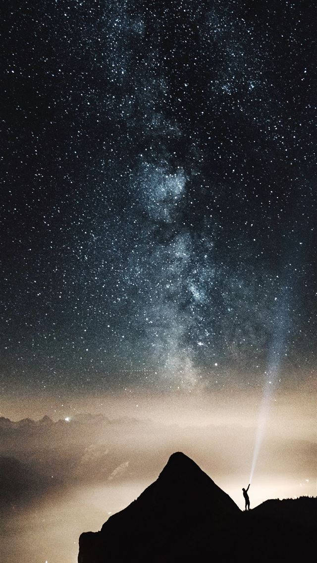 山景 桌布 壁紙 — 夜晚，一個孤獨的身影站在山頂，將手電筒向上照向銀河。