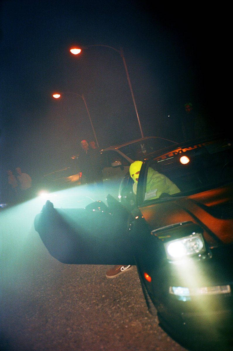 說唱歌手 桌布 壁紙 — 夜晚，一個戴著亮黃色頭盔的人從車門探出身子，車頭燈的光束穿過霧氣。