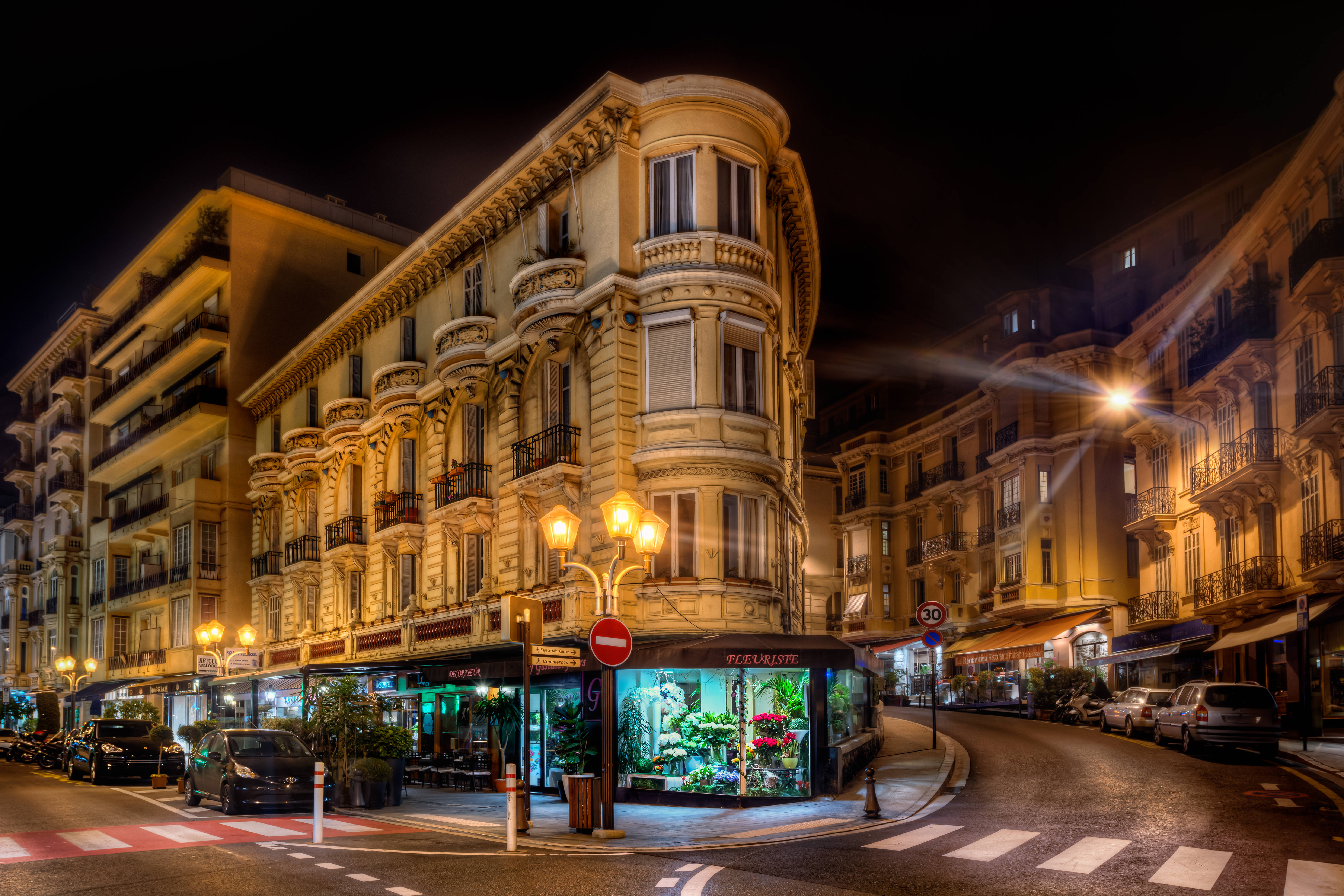 Monaco 桌布 壁紙 — 夜晚，一座宏偉的裝飾建築在彎曲的城市交叉口的街燈下溫暖地發光。