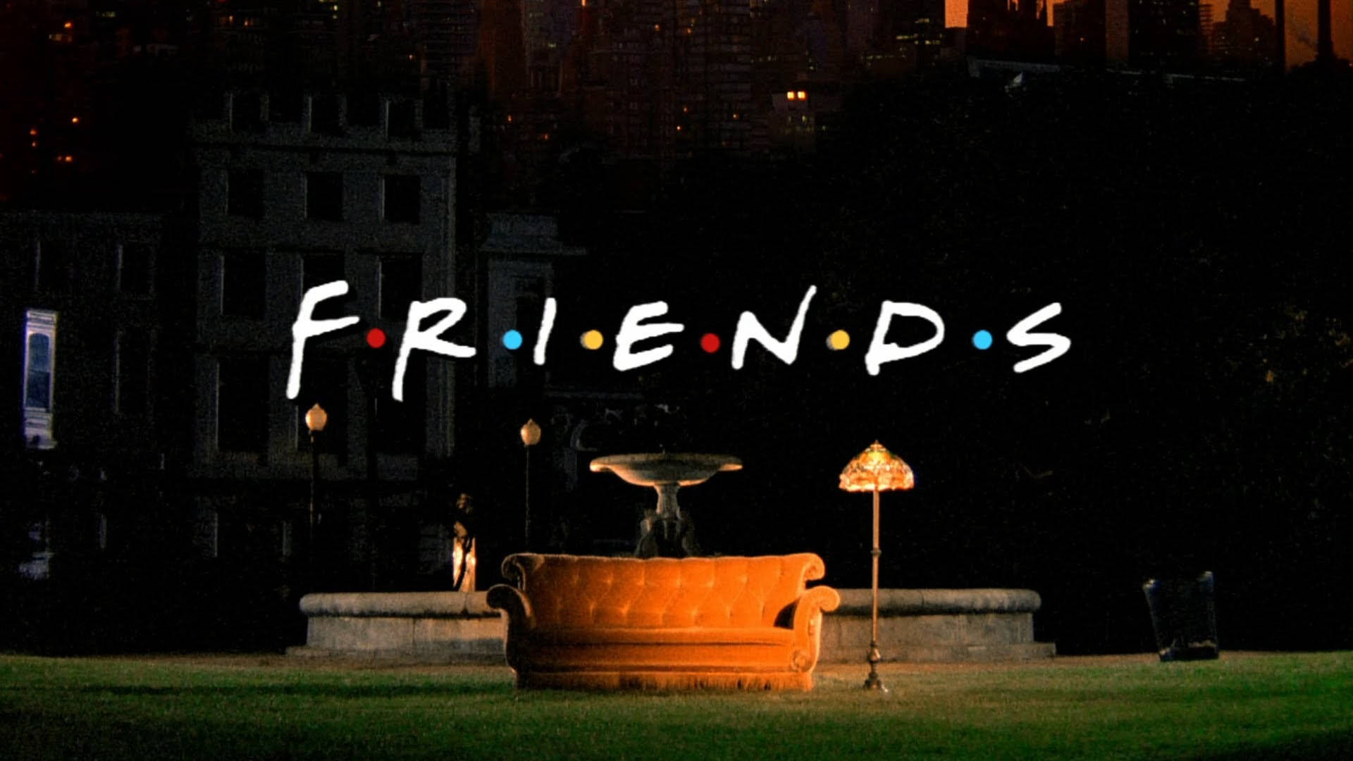 Friends 桌布 壁紙 — 夜晚，一張發光的橙色沙發放在草地上，上方有「FRIENDS」標誌，背後是城市天際線。