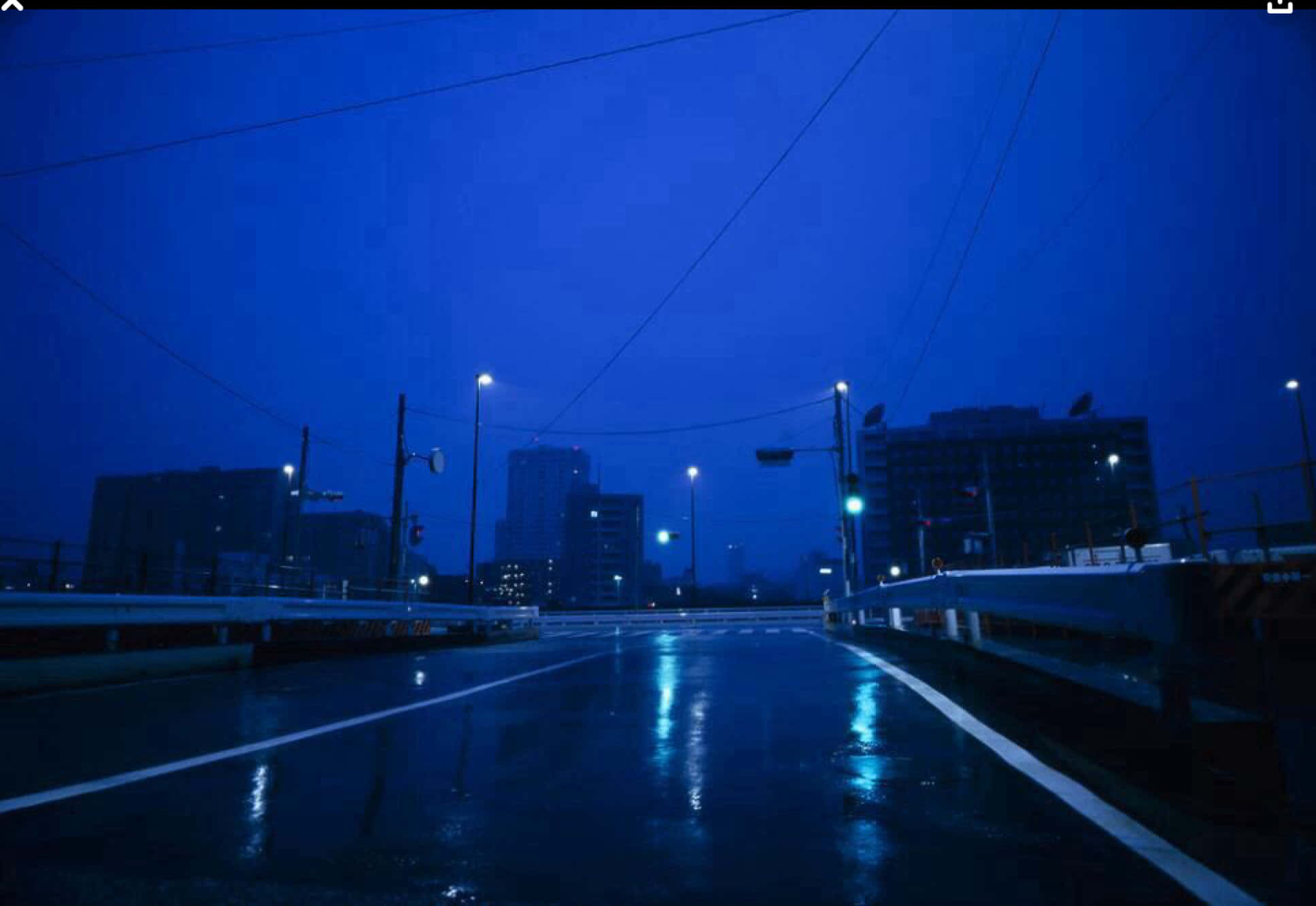 桌布 壁紙 — 夜晚，一條被雨水打濕的城市橋樑在深藍色天空下反射著發光的街燈。