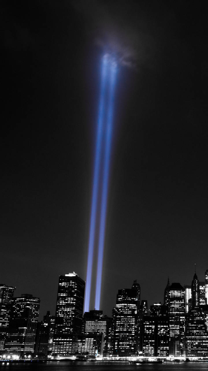 911 Memorial 桌布 壁紙 — 夜晚，兩道強勁的藍色光束從紐約市天際線升起，紀念911襲擊事件。