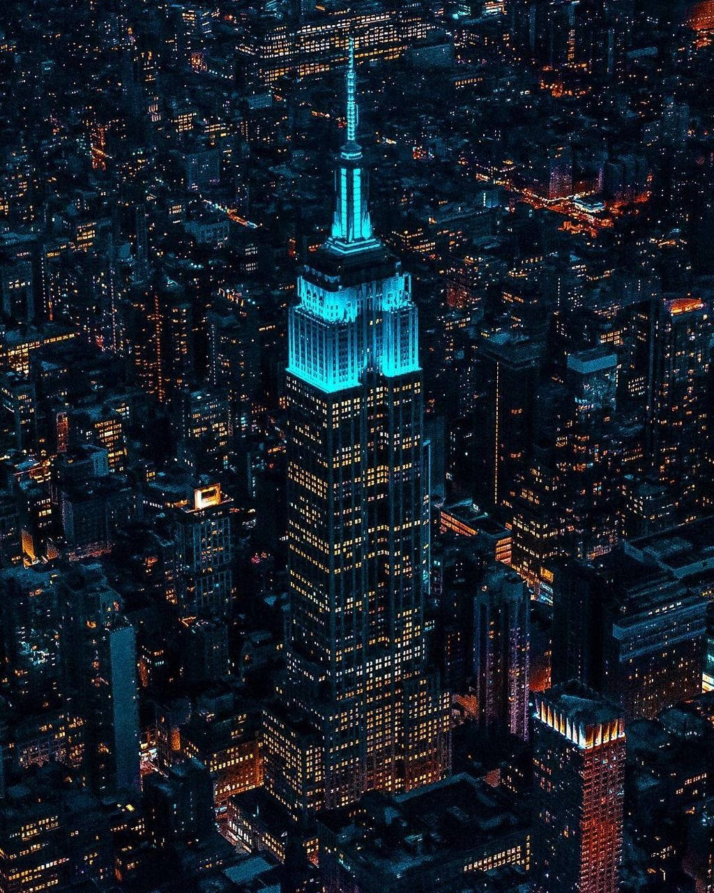 empire 桌布 壁紙 — 夜晚，帝國大廈在黑暗的城市天際線中發出電光藍光的鳥瞰圖。