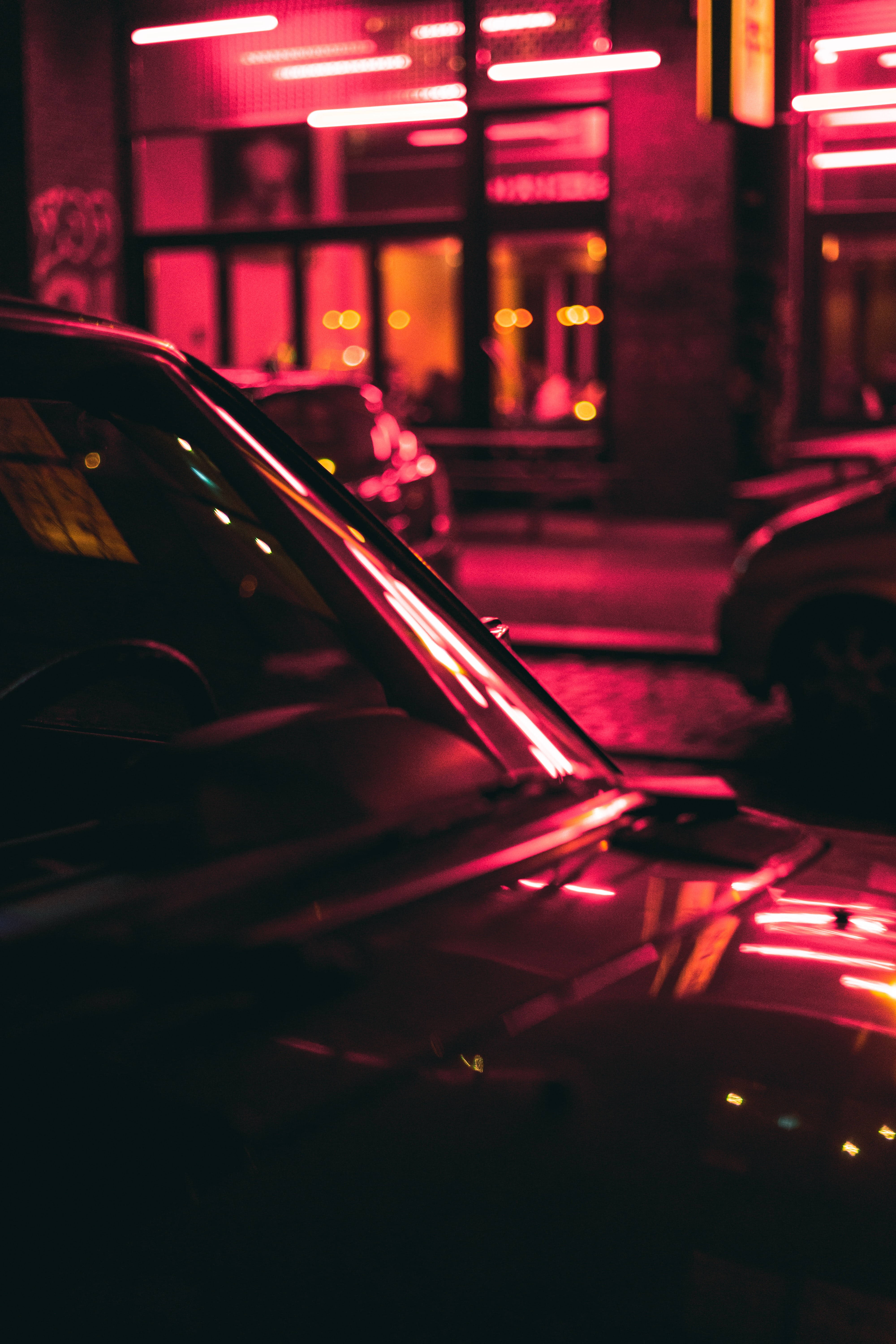 Dark Neon 桌布 壁紙 — 夜晚，時尚汽車的引擎蓋反射出模糊城市商店櫥窗的鮮豔粉紅霓虹燈光。