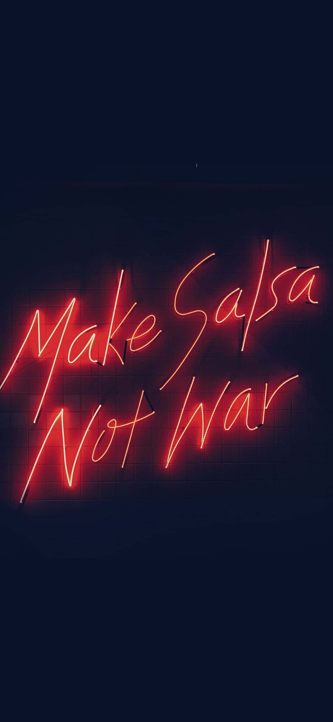 Neon Lights Aesthetic 桌布 壁紙 — 夜晚，深色磚牆上的鮮紅色霓虹燈牌寫著「Make Salsa Not War」。