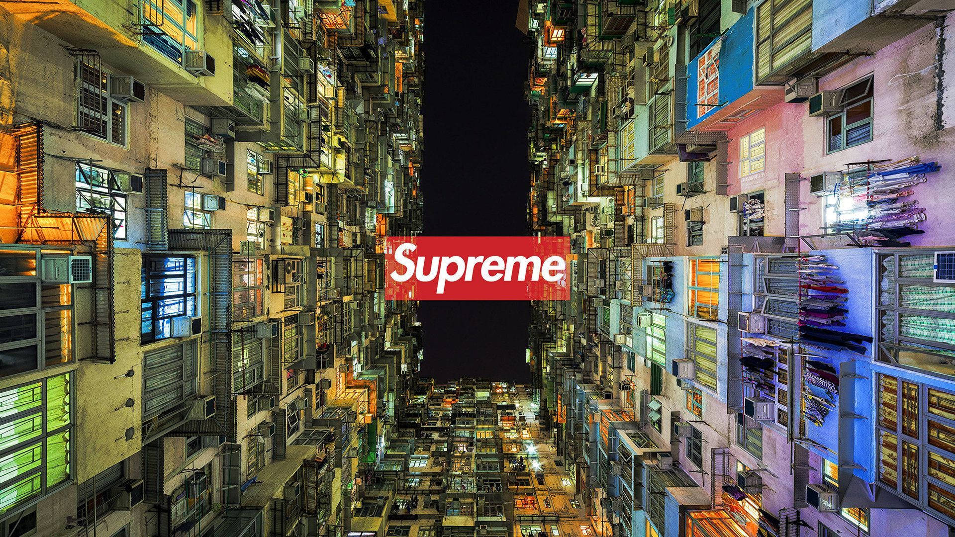 Cool Supreme 桌布 壁紙 — 夜晚，狹窄的小巷兩旁是高聳密集的城市建築，上方虛空中置有紅色Supreme標誌。