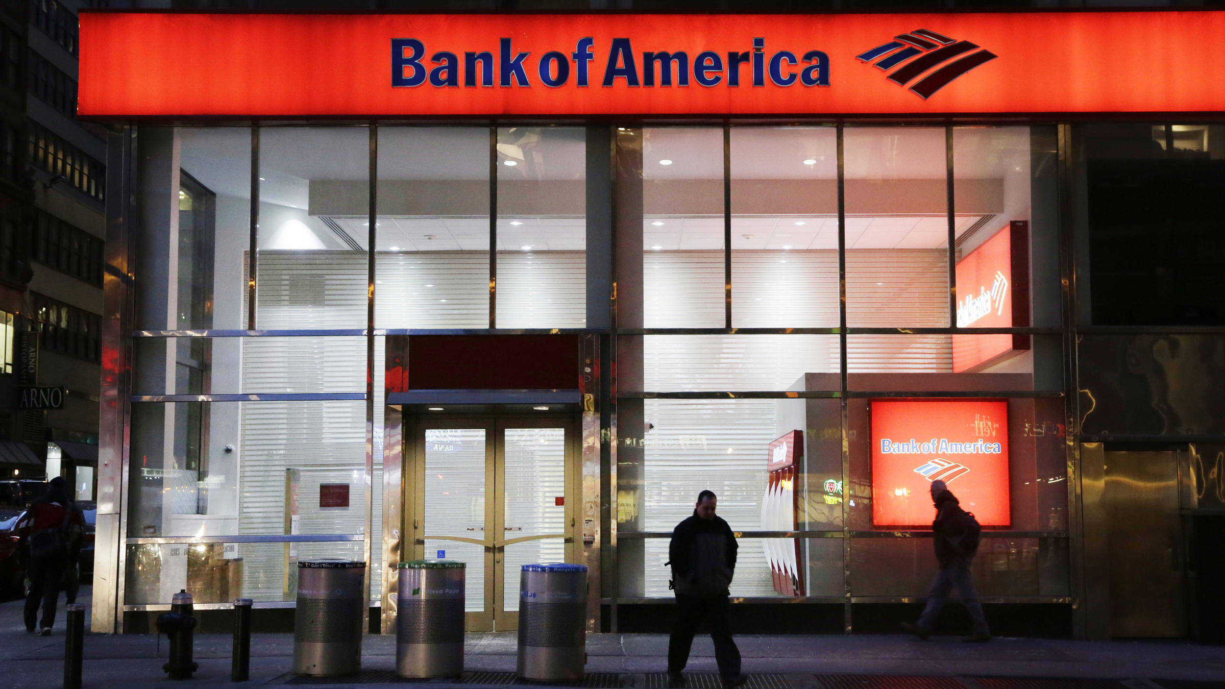 Bank 桌布 壁紙 — 夜晚，行人走過時，一個發光的紅色 Bank of America 標誌照亮了玻璃幕牆的市區銀行。