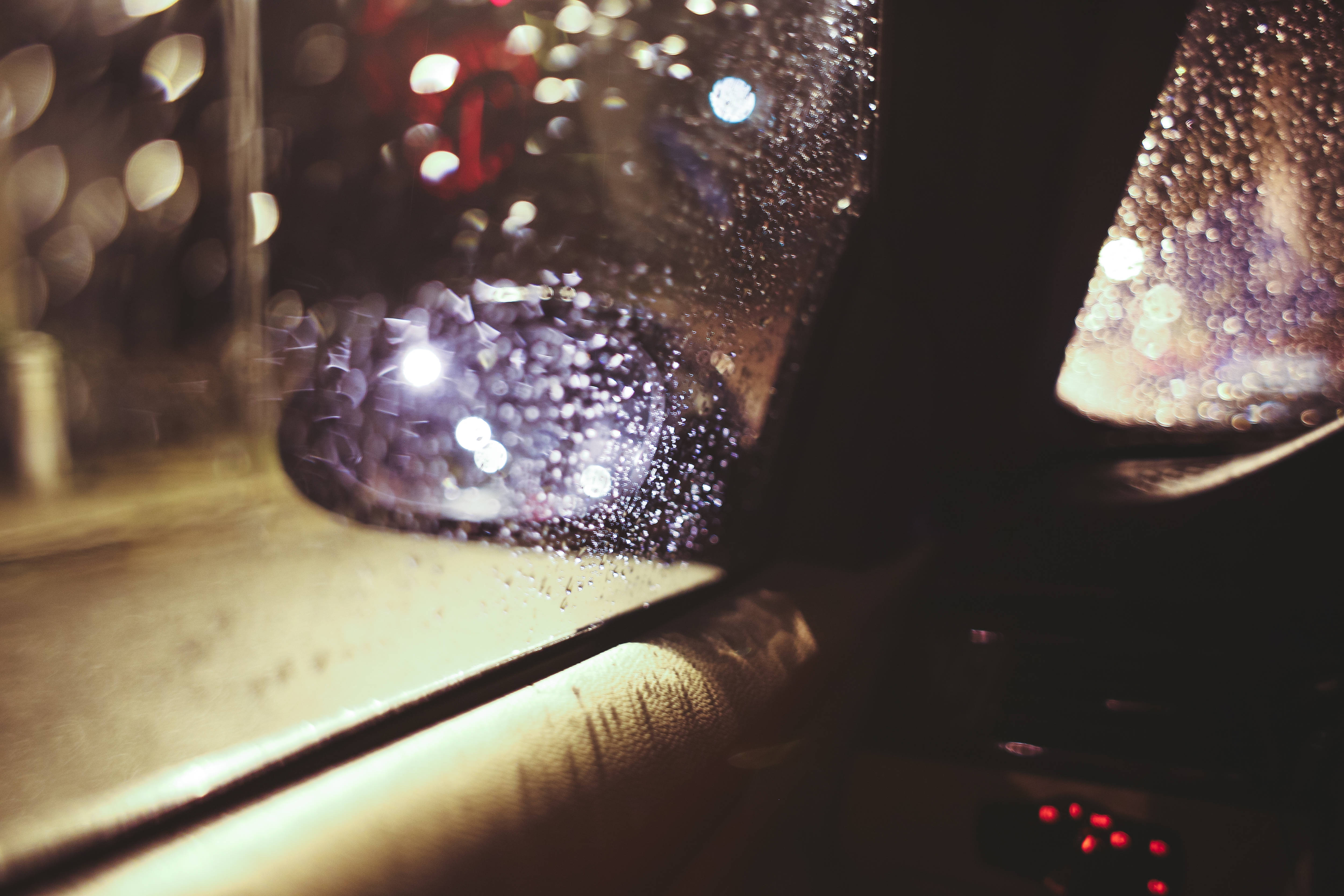 Raining 桌布 壁紙 — 夜晚，雨滴依附在車窗上，將城市燈光模糊成溫暖琥珀色和冷藍色的發光球體。
