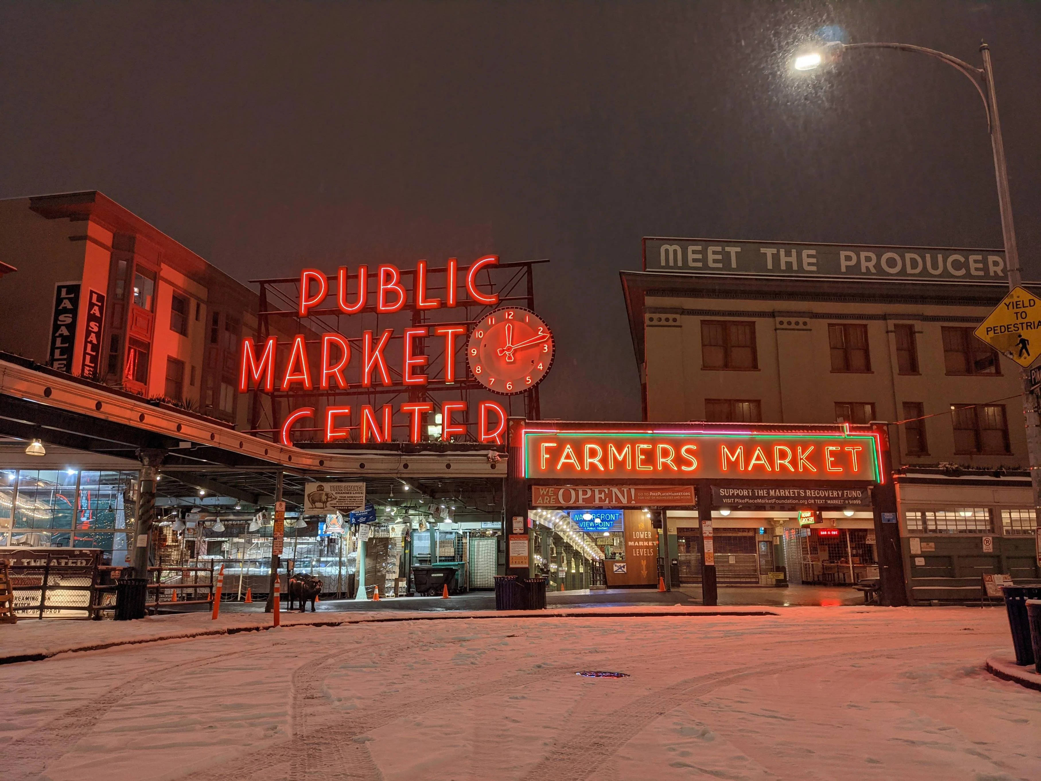 Pike Place Market 桌布 壁紙 — 夜晚，雪覆蓋了公共市場中心發光的紅色霓虹燈招牌下的地面。