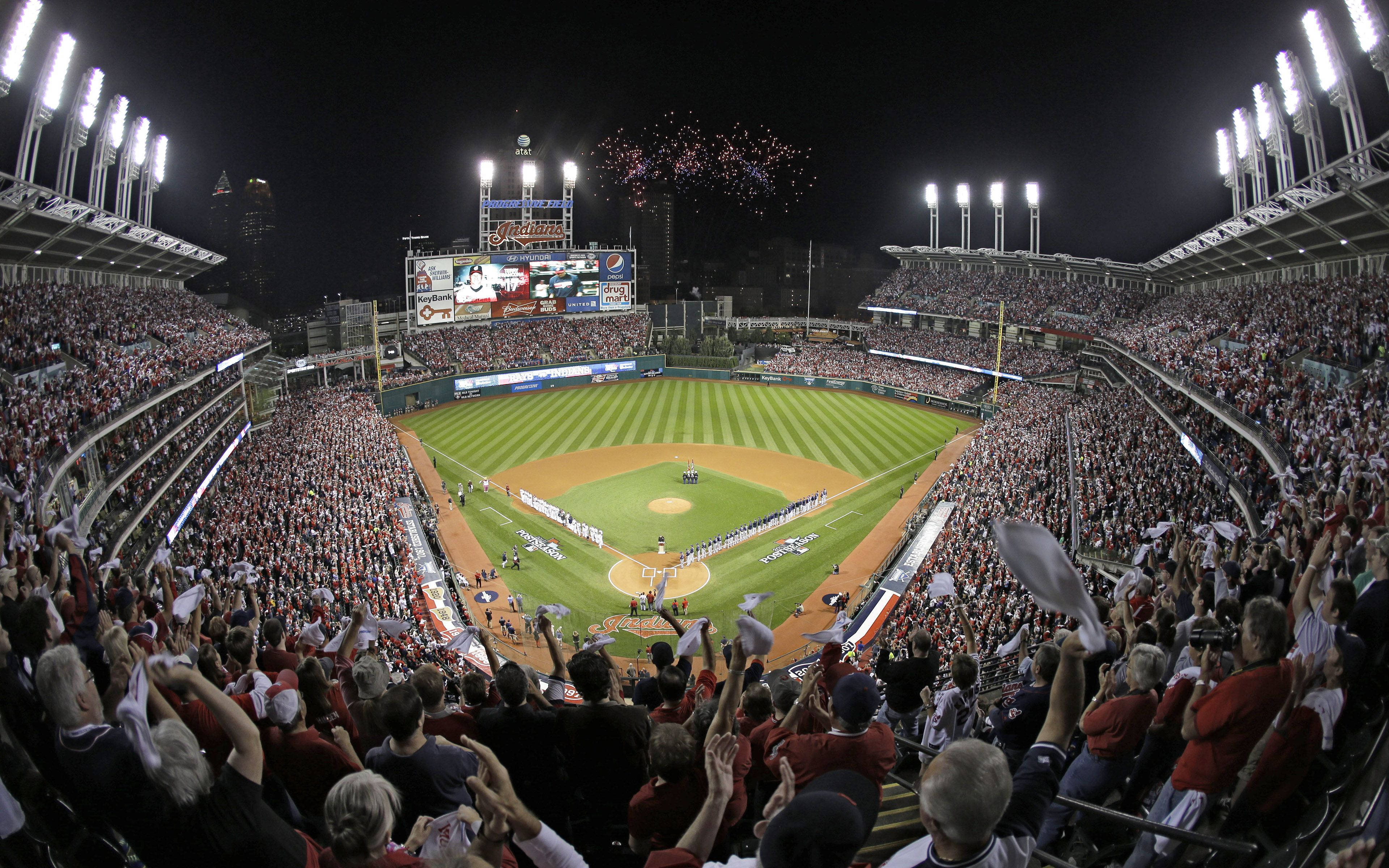 Cleveland Indians 桌布 壁紙 — 夜晚一個擠滿觀眾的棒球場，被明亮的燈光照亮，球場上空綻放煙火，球迷們歡呼雀躍。