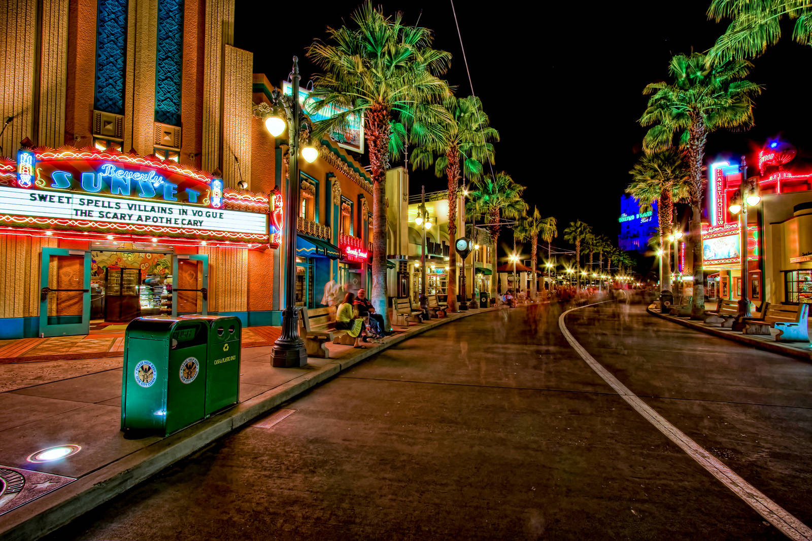 hollywood street 桌布 壁紙 — 夜晚一條充滿活力的霓虹燈街道，棕櫚樹和劇院簷篷在潮濕的人行道反射下閃閃發光。