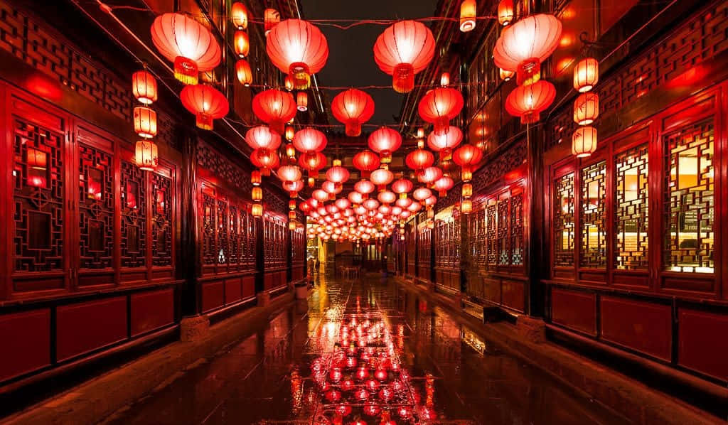 春節 桌布 壁紙 — 夜晚一條狹窄潮濕的小巷，被發光的紅燈籠照亮，倒映在光滑的路面上。