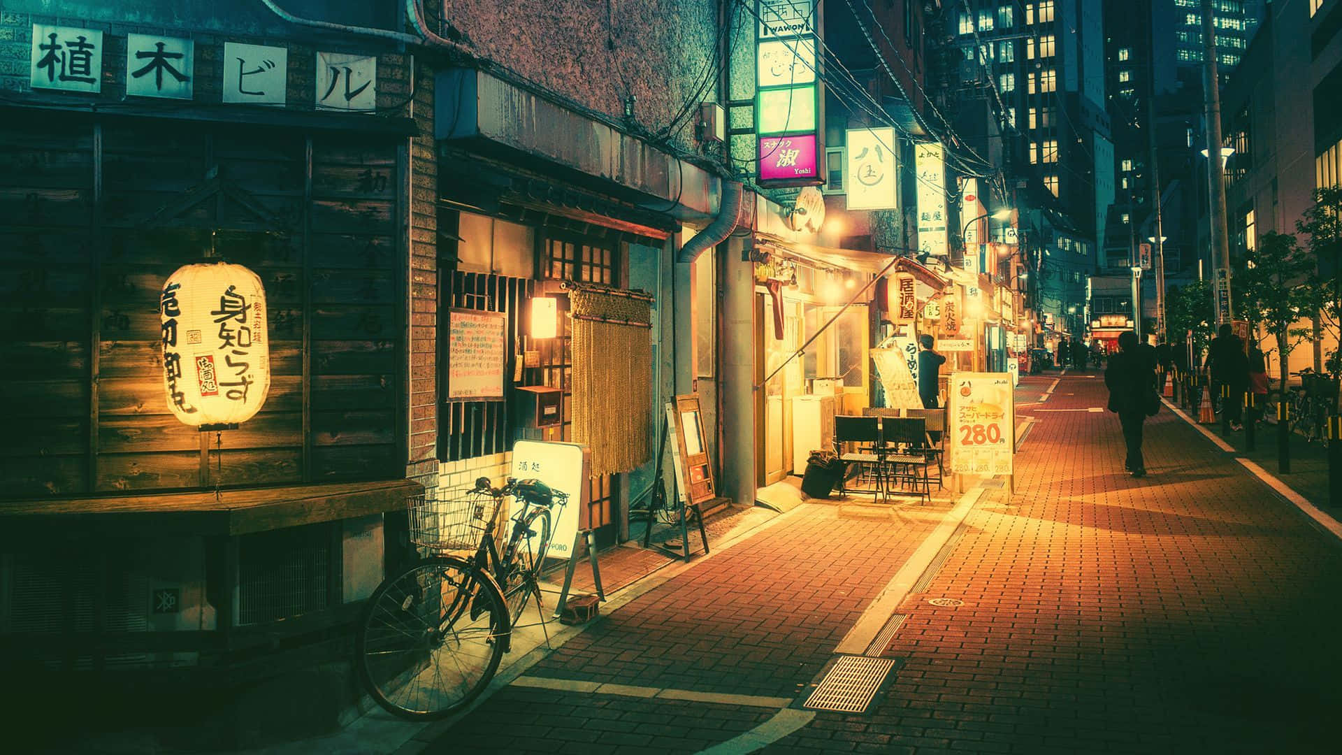 城市 桌布 壁紙 — 夜晚一條狹窄的日本街道，沐浴在溫暖的燈籠光芒中，有木製商店和外面停著的一輛孤獨自行車。