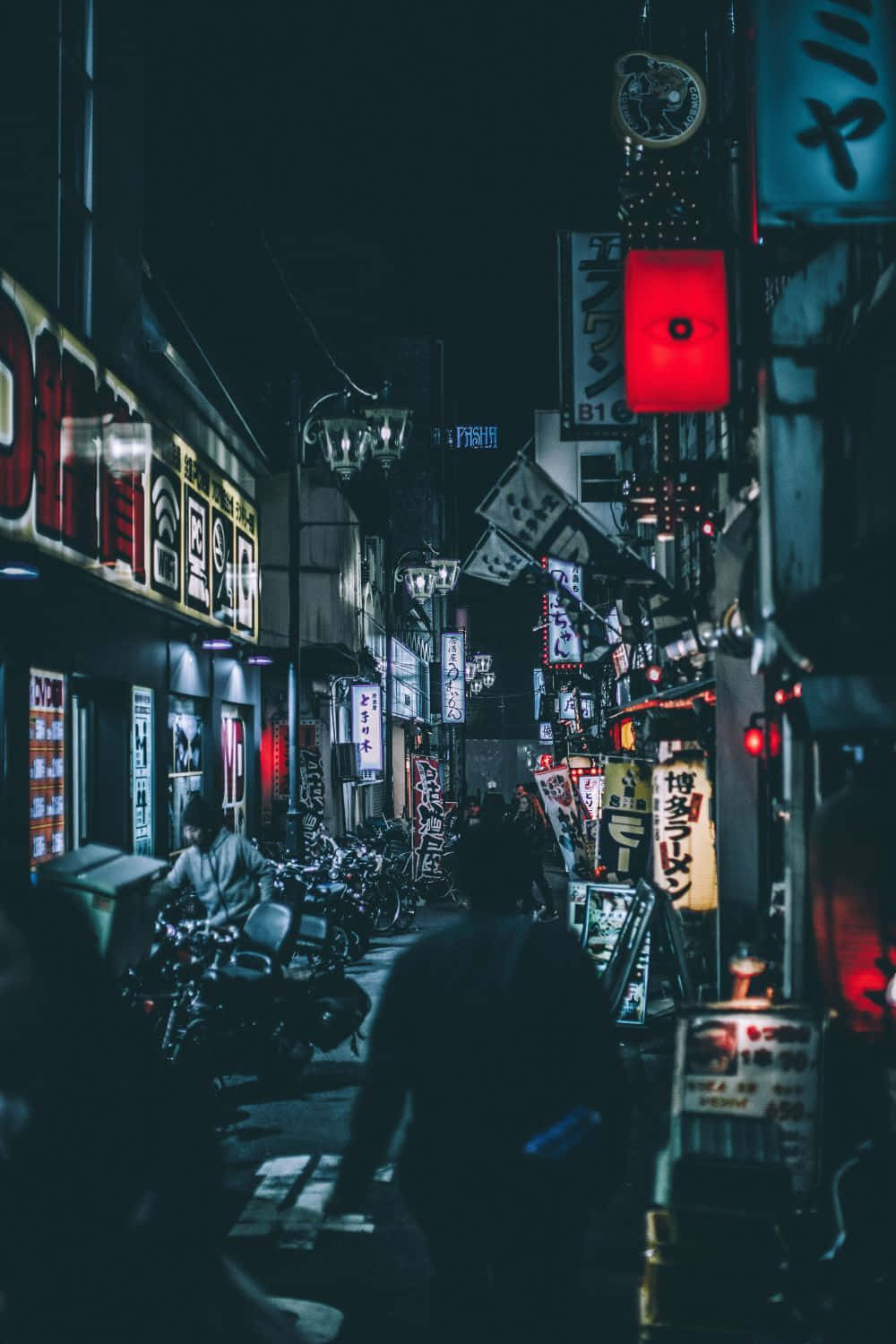 紅色美學動圖 桌布 壁紙 — 夜晚一條狹窄的東京小巷，被發光的霓虹燈招牌和街燈照亮，在濕漉漉的人行道上投射出色彩繽紛的倒影。