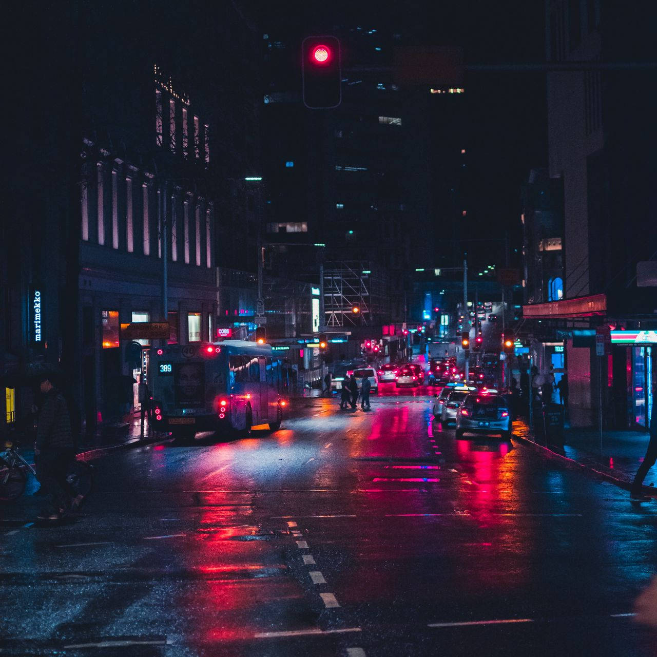 桌布 壁紙 — 夜晚一條被霓虹燈浸透的城市街道，潮濕的路面反射著交通和商店櫥窗的紅藍燈光。