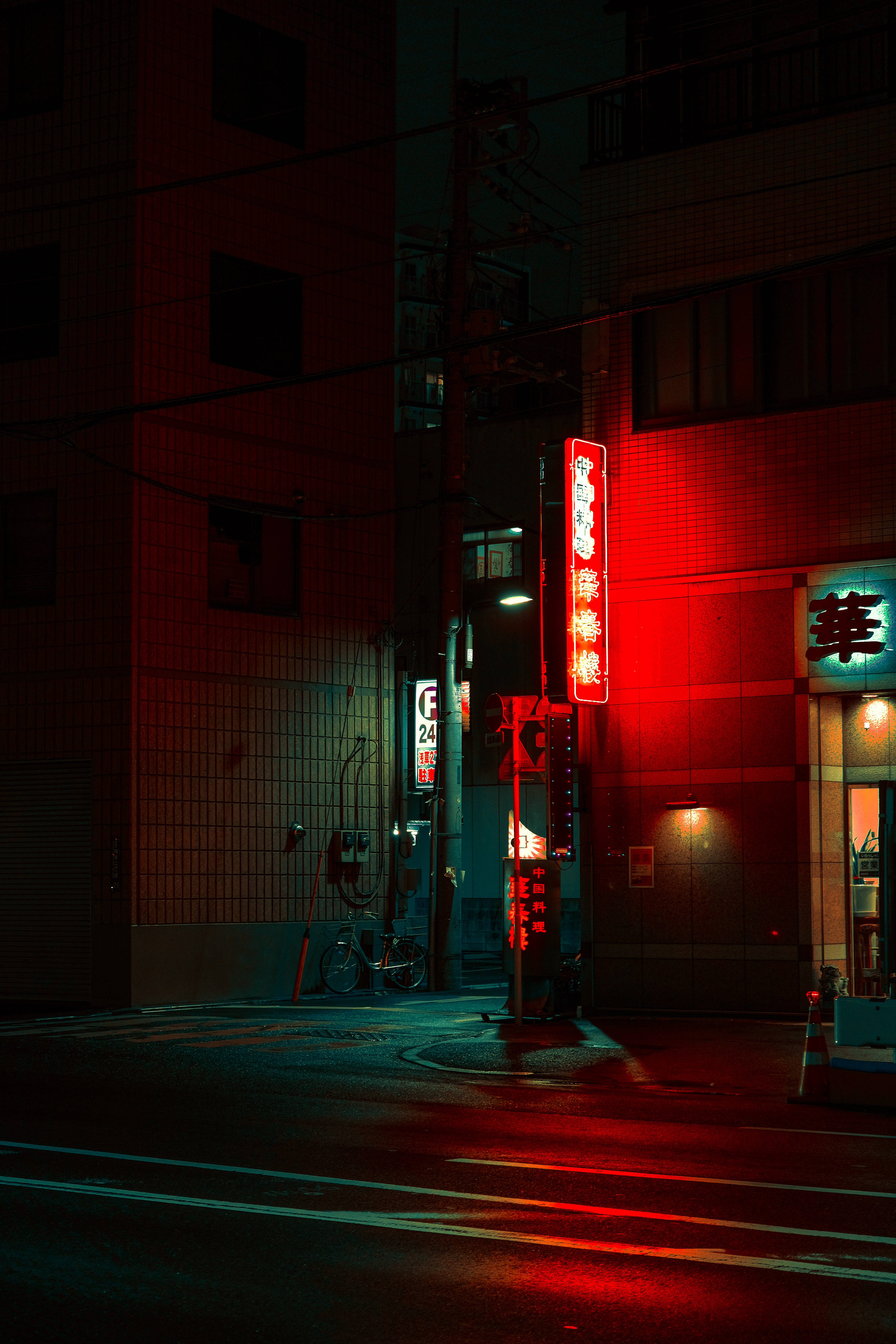 東京 桌布 壁紙 — 夜晚一條被霓虹燈照亮的城市小巷，沐浴在發光招牌的紅色光芒中，反射在濕漉漉的路面上。