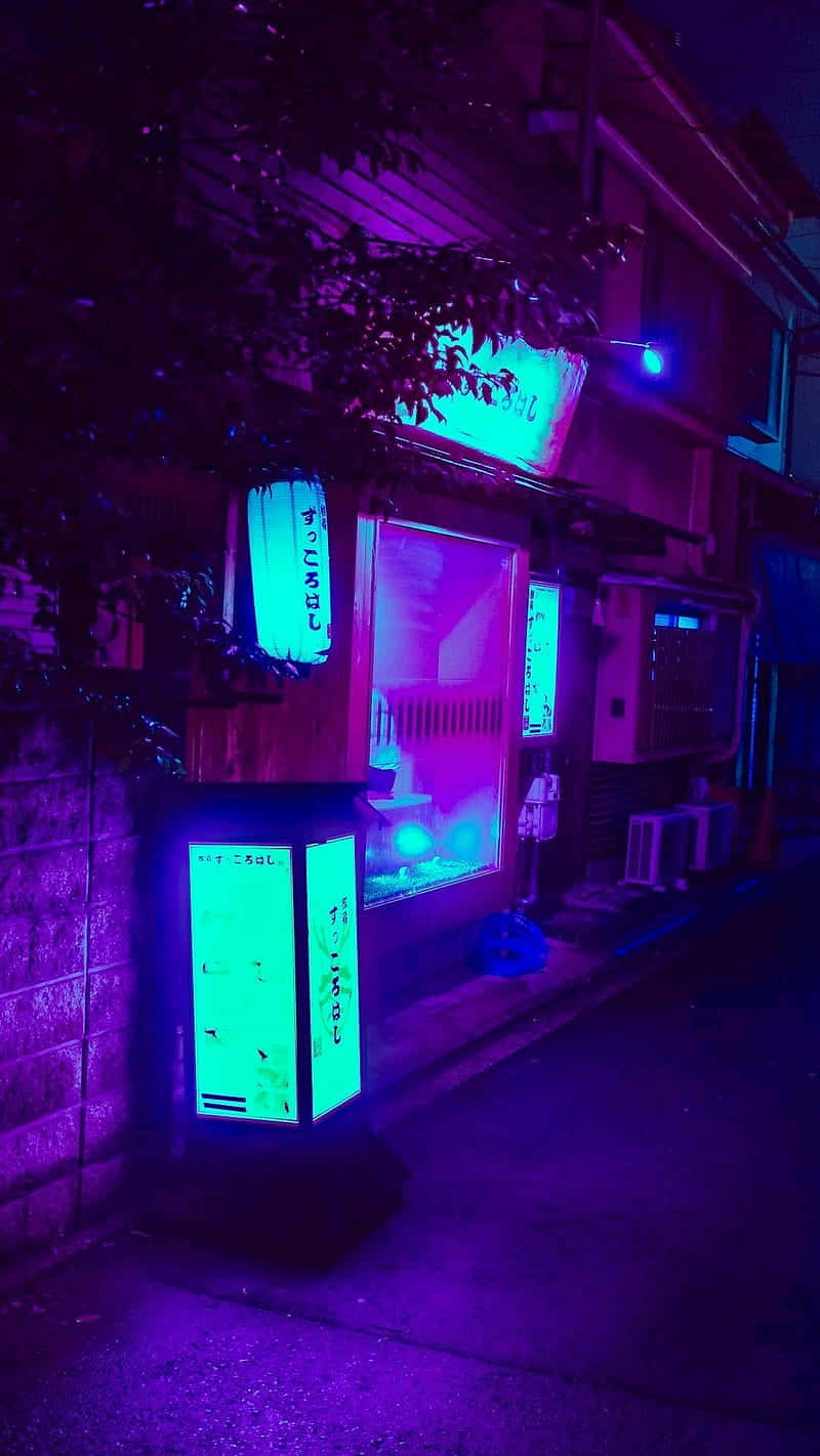 桌布 壁紙 — 夜晚一條霓虹燈照亮的小巷，有發光的綠色自動販賣機和紫色環境燈光，在磚牆和樹木上投下陰影。