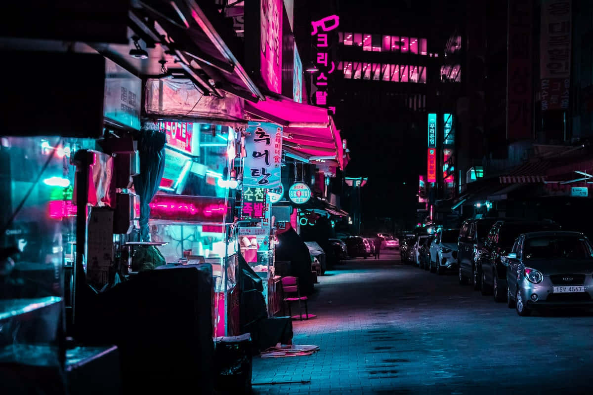 夜晚 桌布 壁紙 — 夜晚一條霓虹燈照亮的小巷，發光的粉紅色和藍色招牌映照在潮濕的路面和停泊的汽車上。
