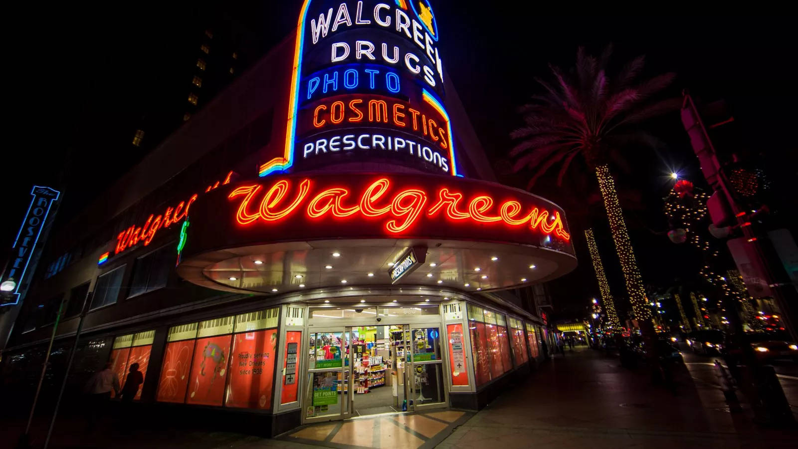 LED 桌布 壁紙 — 夜晚一間充滿活力的Walgreens商店，霓虹燈閃爍，棕櫚樹排列在人行道上。