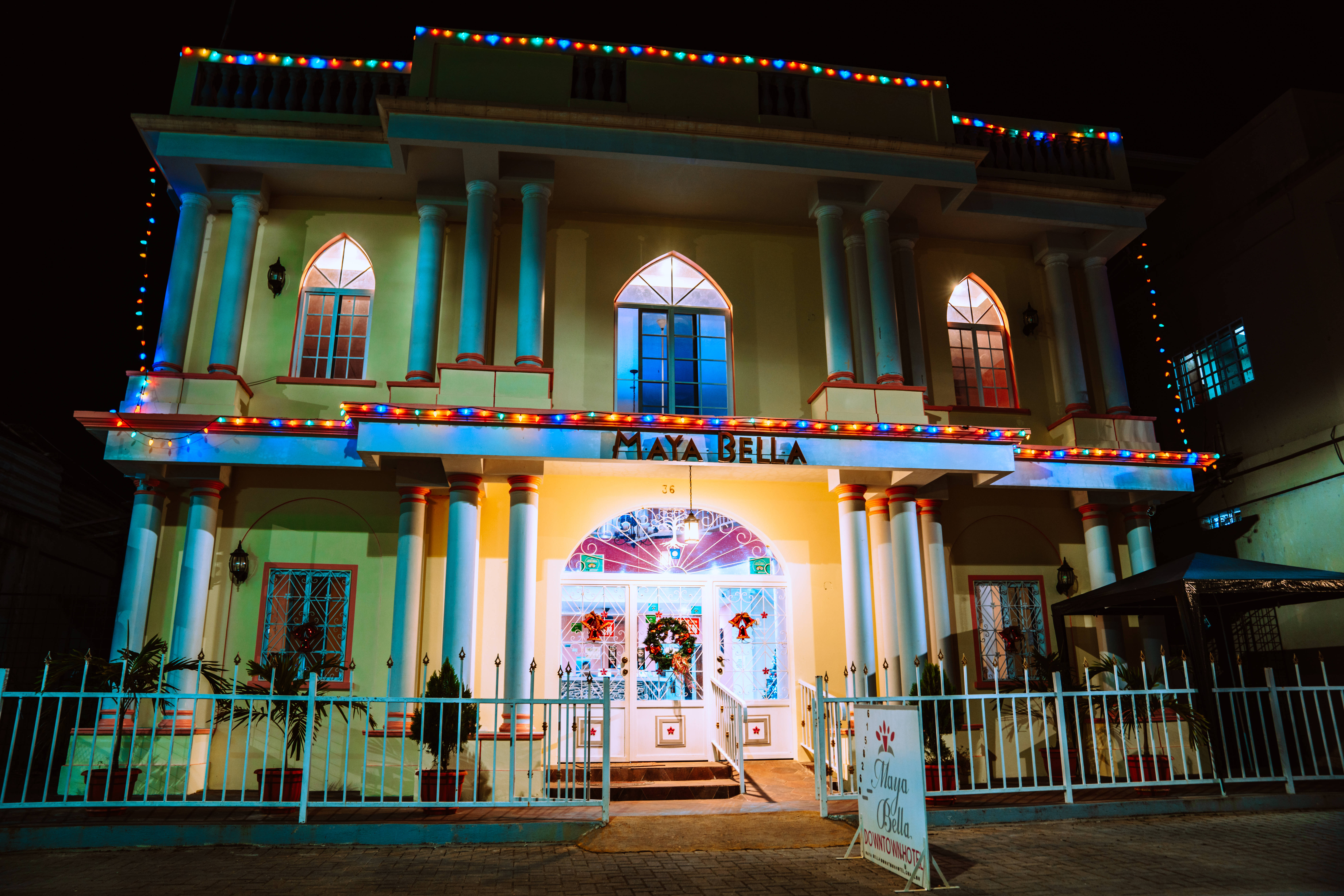 Belize 桌布 壁紙 — 夜晚中，一棟名為Maya Bella的兩層建築燈火通明，裝飾著彩色燈串和發光的窗戶。