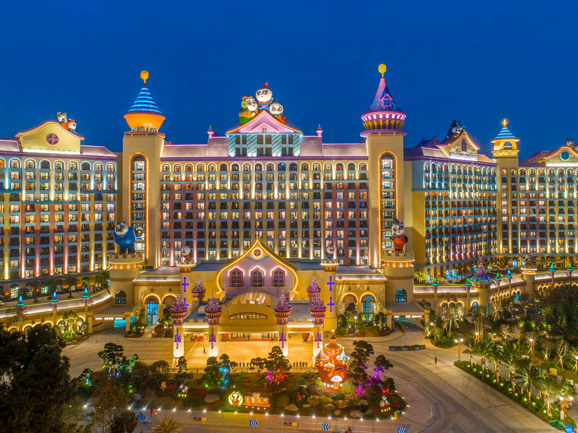 Guangzhou 桌布 壁紙 — 夜晚中宏偉的燈光度假村建築，裝飾著色彩繽紛的卡通人物雕像和鮮豔的燈光。