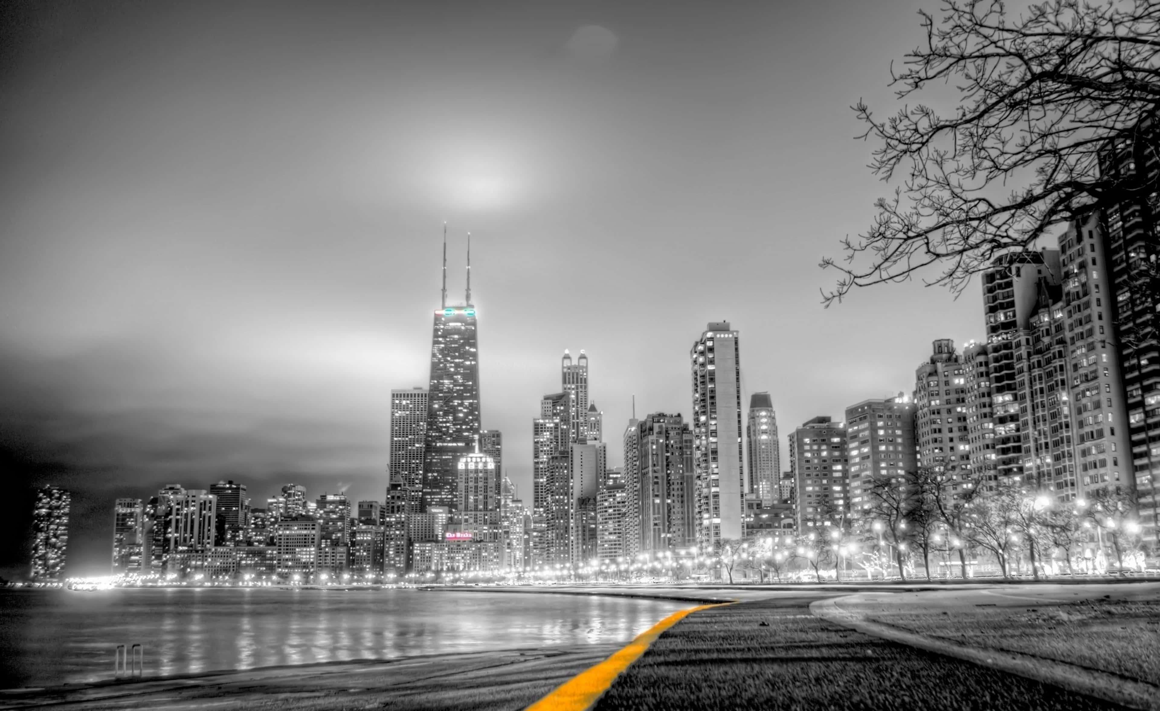 桌布 壁紙 — 夜晚令人驚嘆的黑白城市景觀，一條充滿活力的黃色小徑通向水中倒映的高聳摩天大樓。
