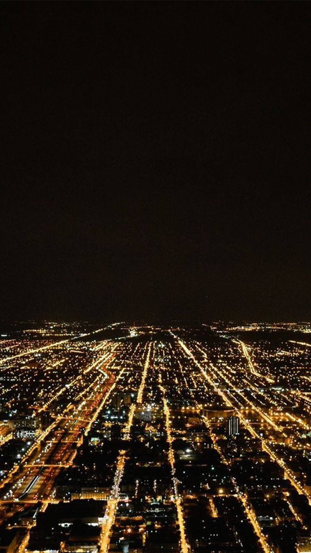 View 桌布 壁紙 — 夜晚俯瞰一座廣闊的城市，黑暗的天空下閃爍的街燈和建築物。