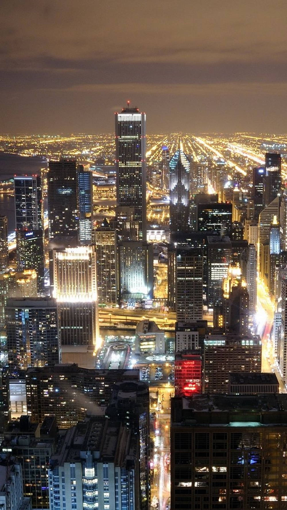 New York 桌布 壁紙 — 夜晚俯瞰廣闊城市，高聳摩天大樓與下方閃爍街道的航拍景象。