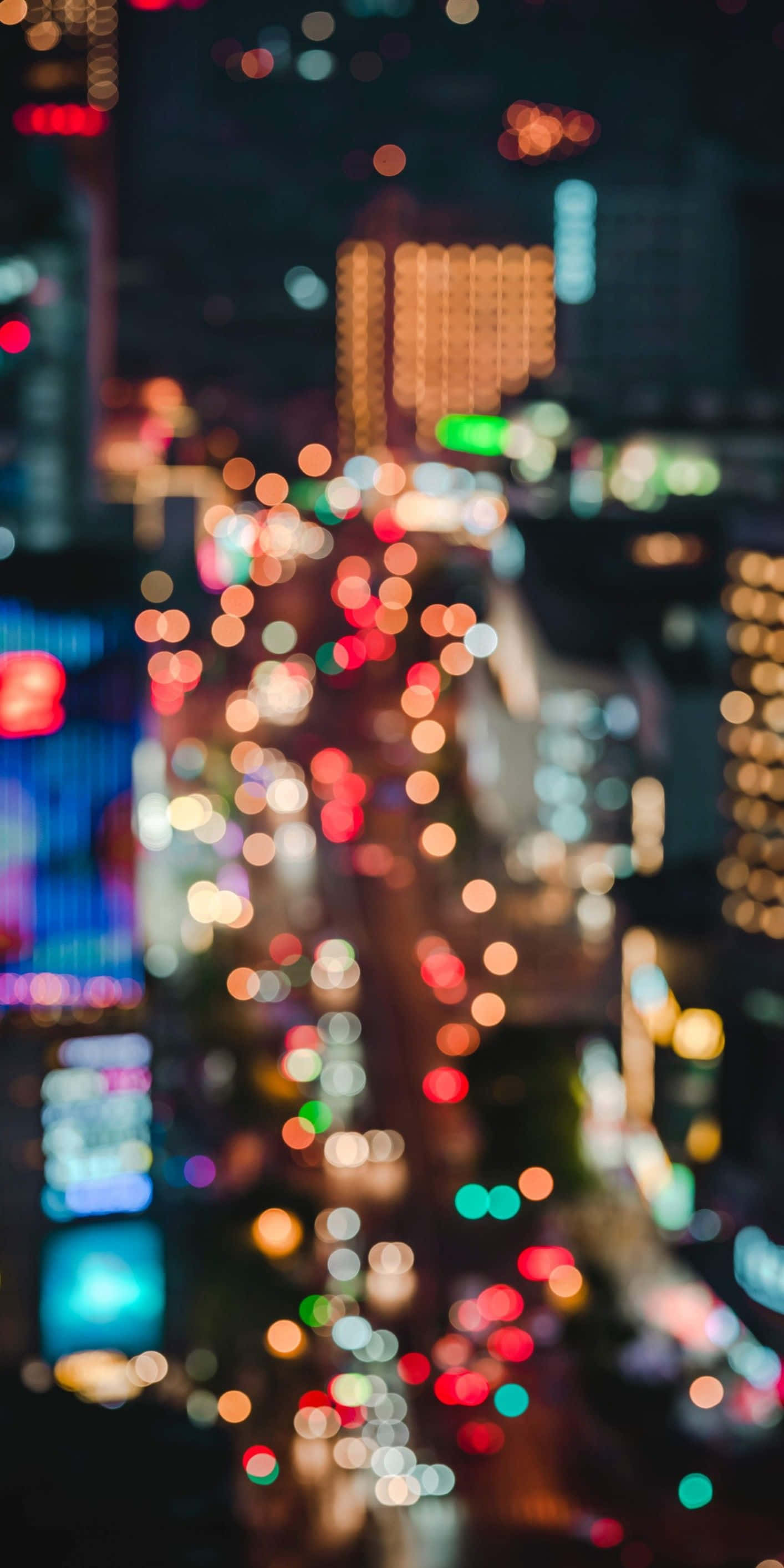 City Lights 桌布 壁紙 — 夜晚充滿活力的散景城市景觀，建築物和街道散發出紅色、藍色和黃色的發光球體。