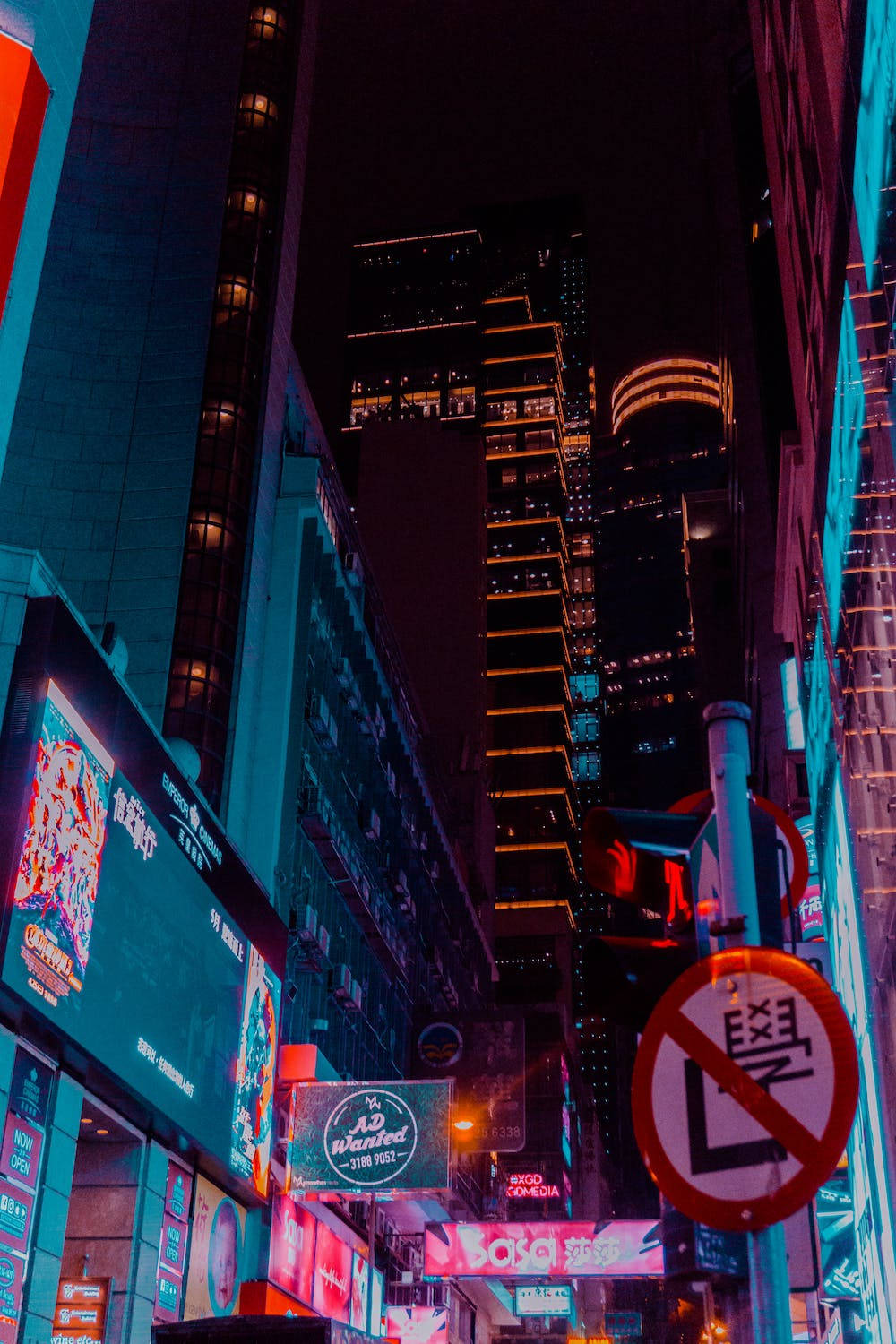 城市 桌布 壁紙 — 夜晚充滿活力的霓虹燈城市小巷，高聳的摩天大樓散發著電光藍和橙色的色調。