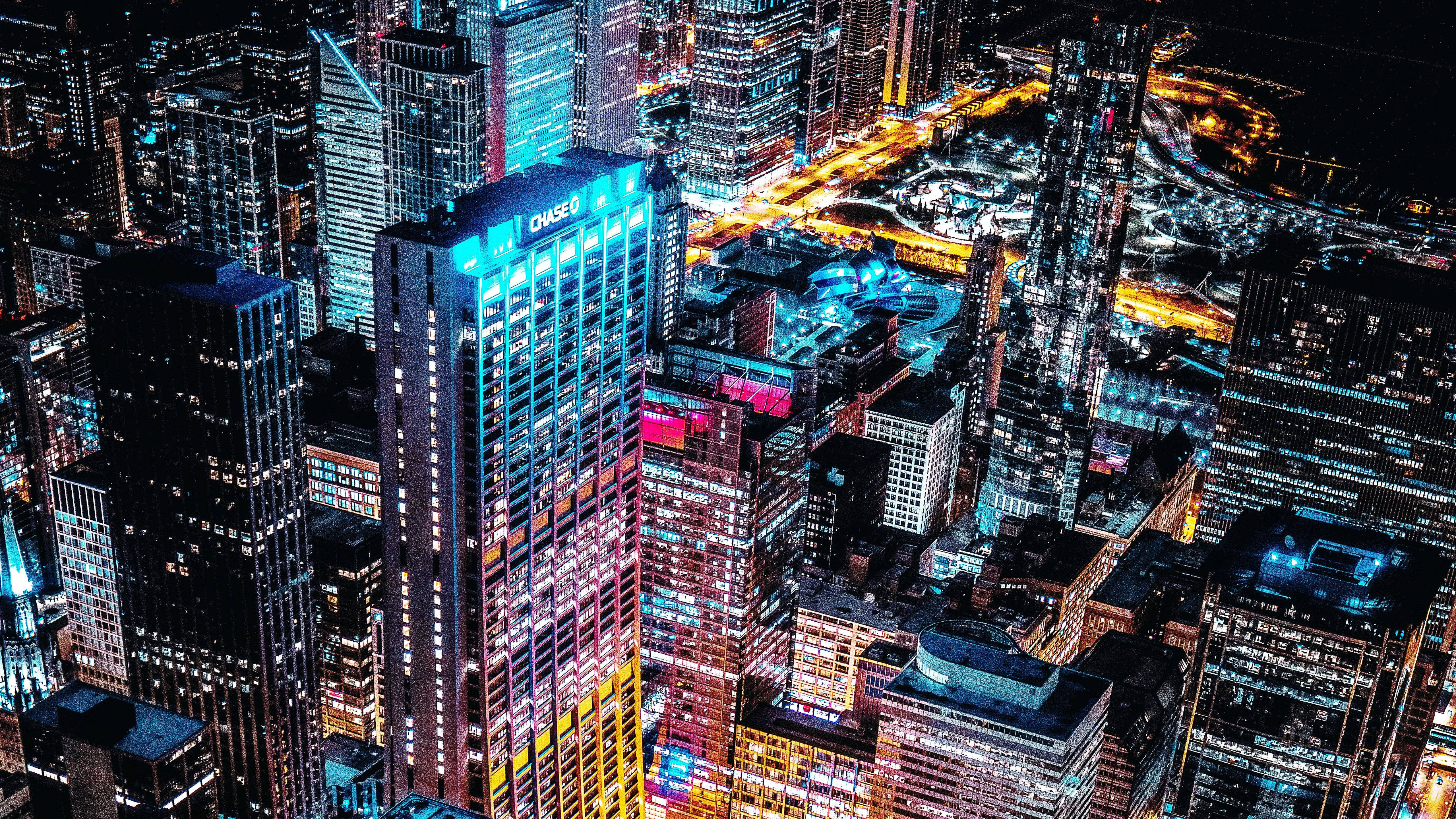 View 桌布 壁紙 — 夜晚充滿活力的霓虹燈城市景觀鳥瞰圖，高聳的摩天大樓和發光的街道。