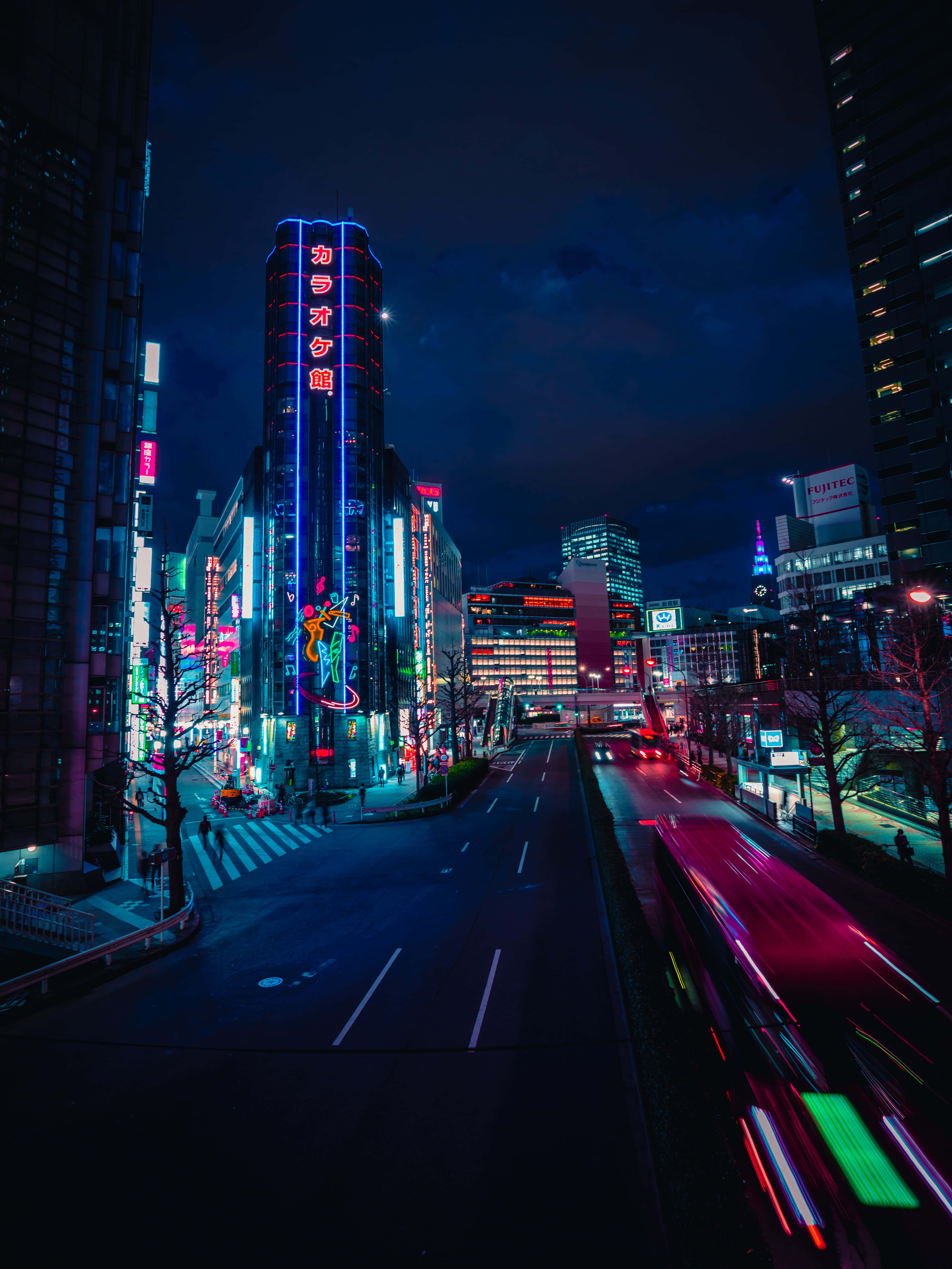 Street 桌布 壁紙 — 夜晚充滿活力的霓虹燈城市街道，有發光的招牌和汽車燈光拖影。