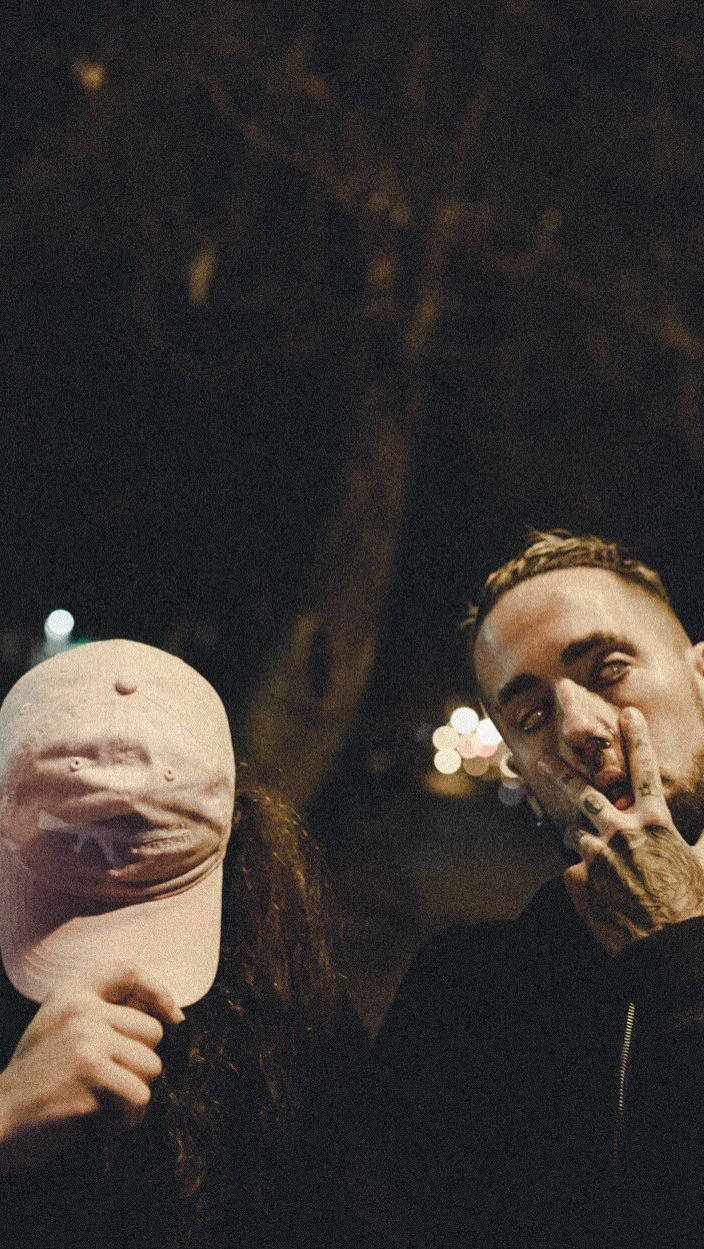 suicideboys 桌布 壁紙 — 夜晚兩個人，一人用帽子遮住臉，另一人在昏暗街燈下抽煙，紋身可見。
