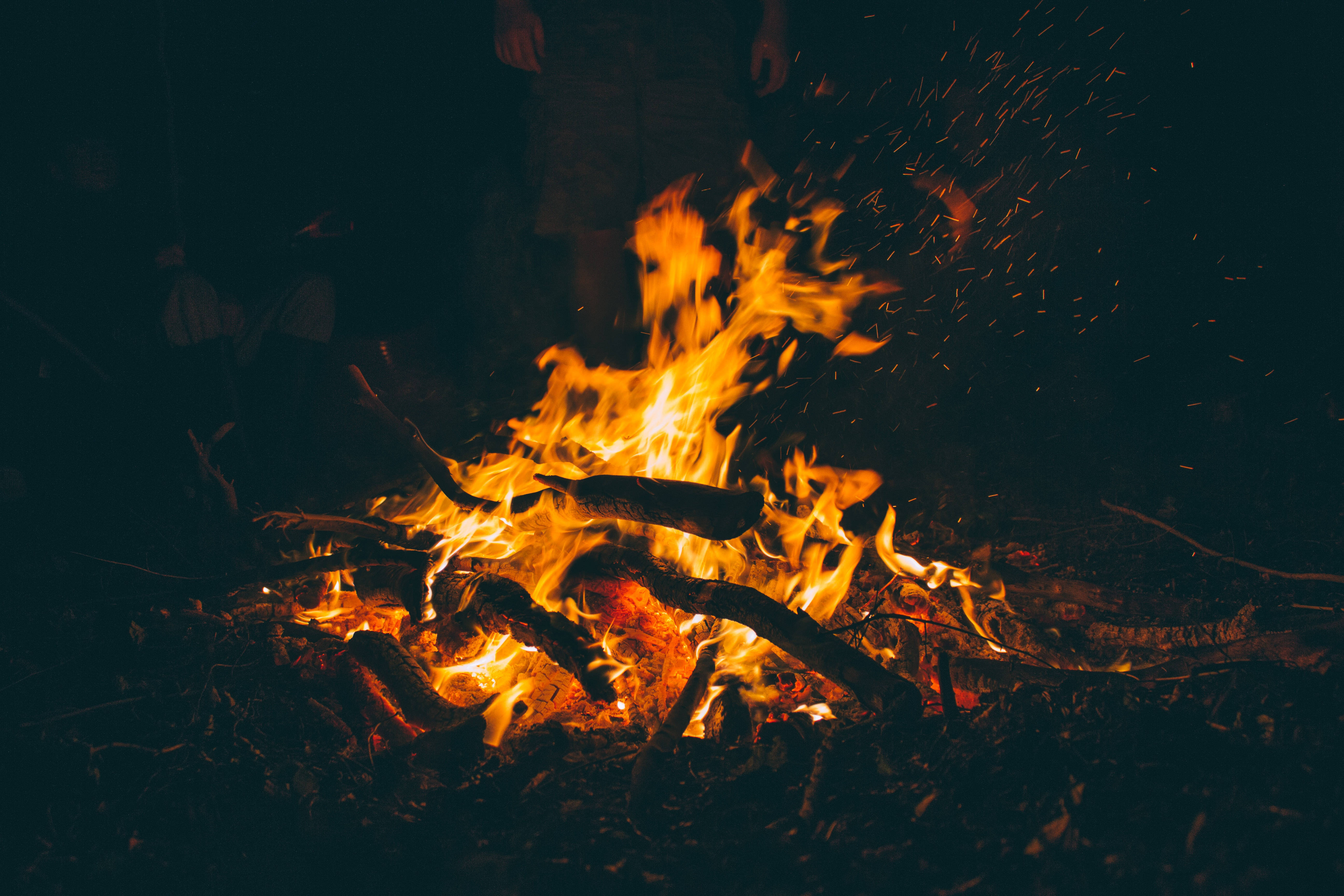 火焰動畫 桌布 壁紙 — 夜晚咆哮的營火，明亮的橙色火焰和飛舞的火星照亮了黑暗的環境。
