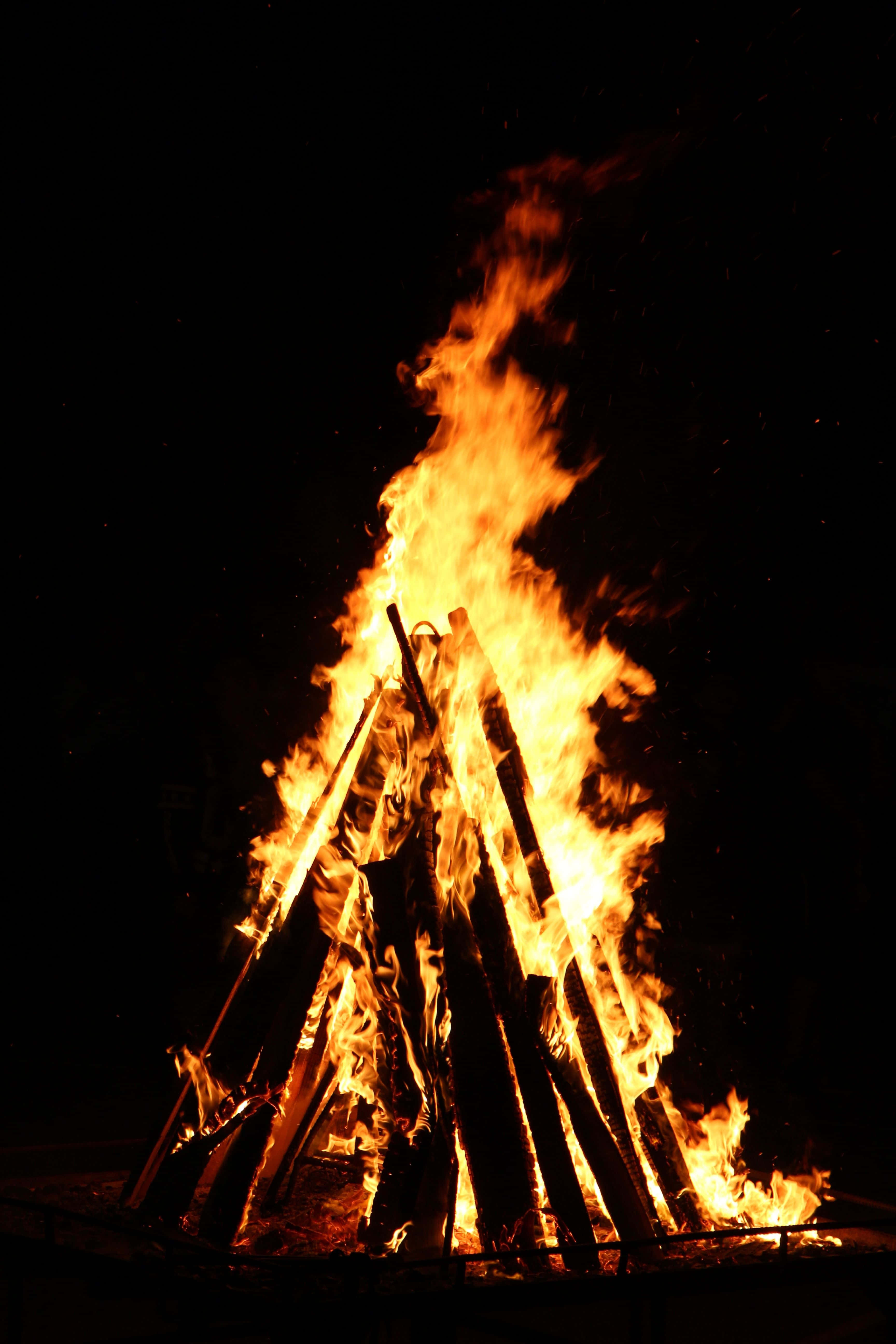 Campfire 桌布 壁紙 — 夜晚咆哮的營火，明亮的橙色火焰在漆黑的天空中跳躍。