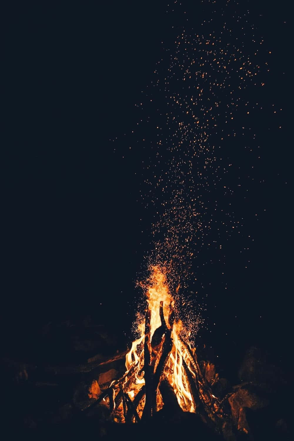 Campfire 桌布 壁紙 — 夜晚咆哮的營火向漆黑的天空噴射出明亮的橙色火花。