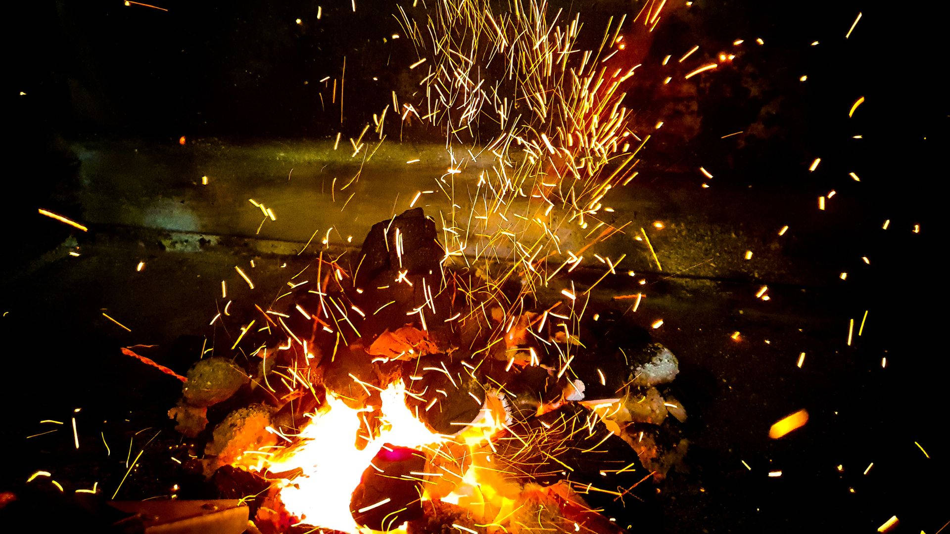 火焰動畫 桌布 壁紙 — 夜晚咆哮的營火在黑暗背景下飛舞著金色火花。