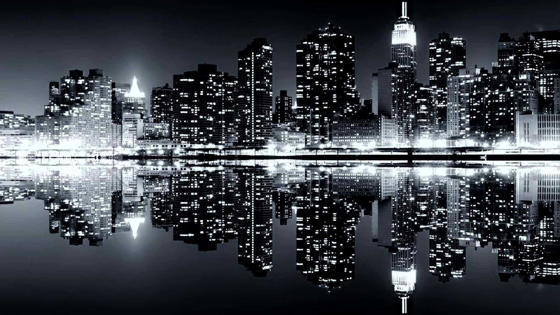 Black And White Cityscape 桌布 壁紙 — 夜晚單色城市天際線，摩天大樓完美倒映在平靜的水面上。
