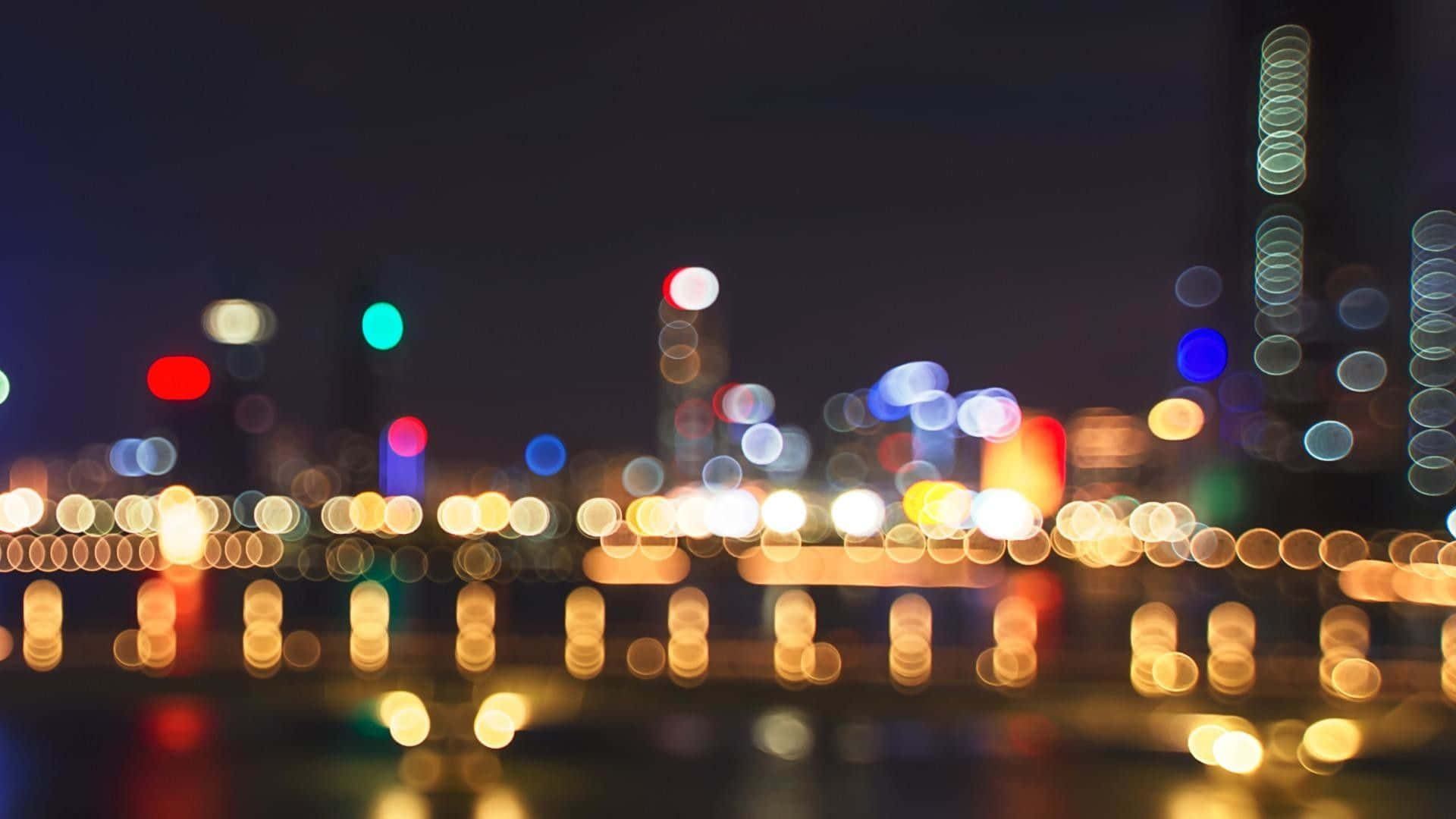 lights 桌布 壁紙 — 夜晚城市天際線的散景燈光倒映在水中，營造出夢幻般的發光效果。